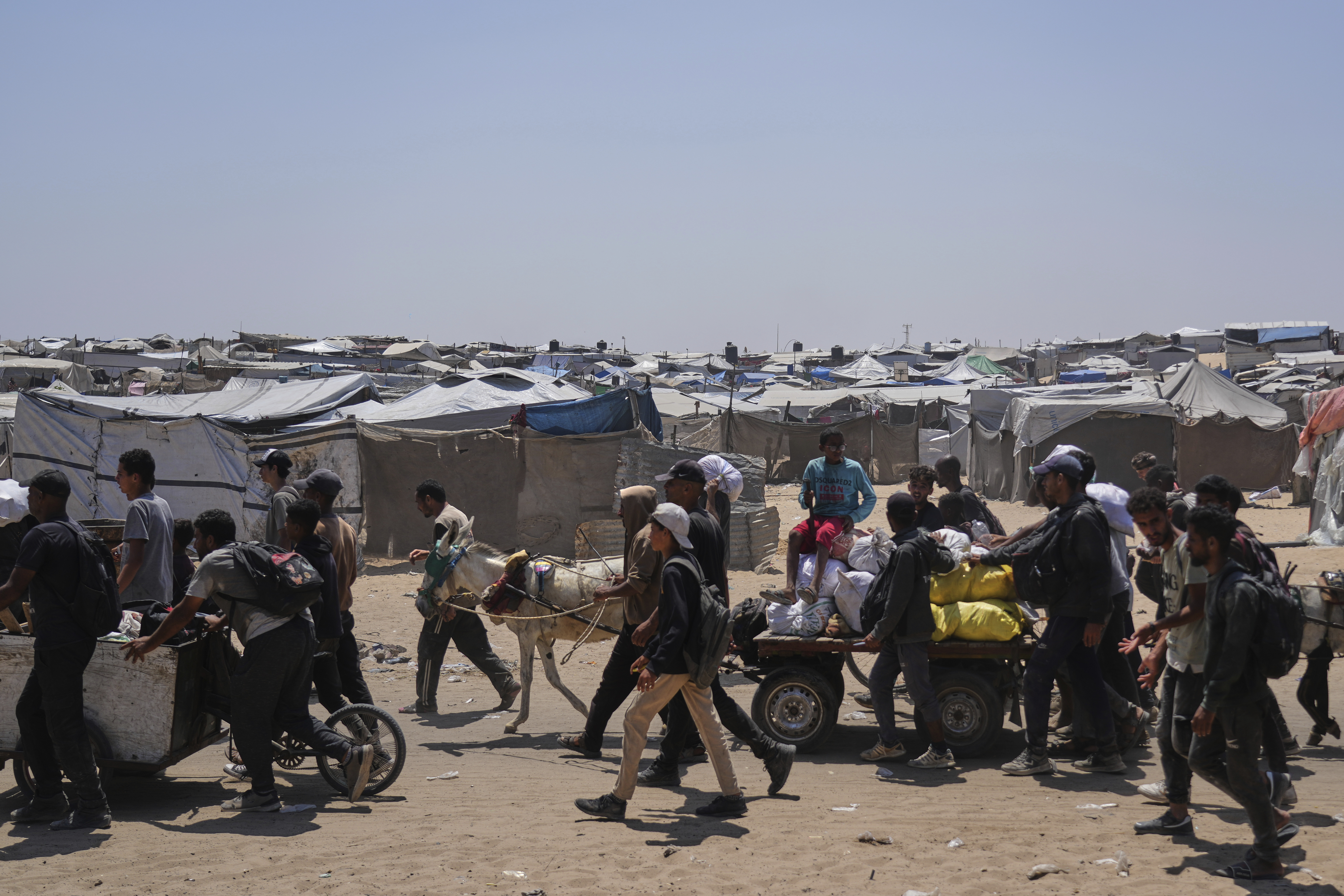 Palestinians carry bags containing food and humanitarian aid packages delivered by the Gaza Humanitarian Foundation, a U.S.-backed organization, in Rafah, southern Gaza Strip, Monday, June 16, 2025. (AP Photo/Abdel Kareem Hana)
