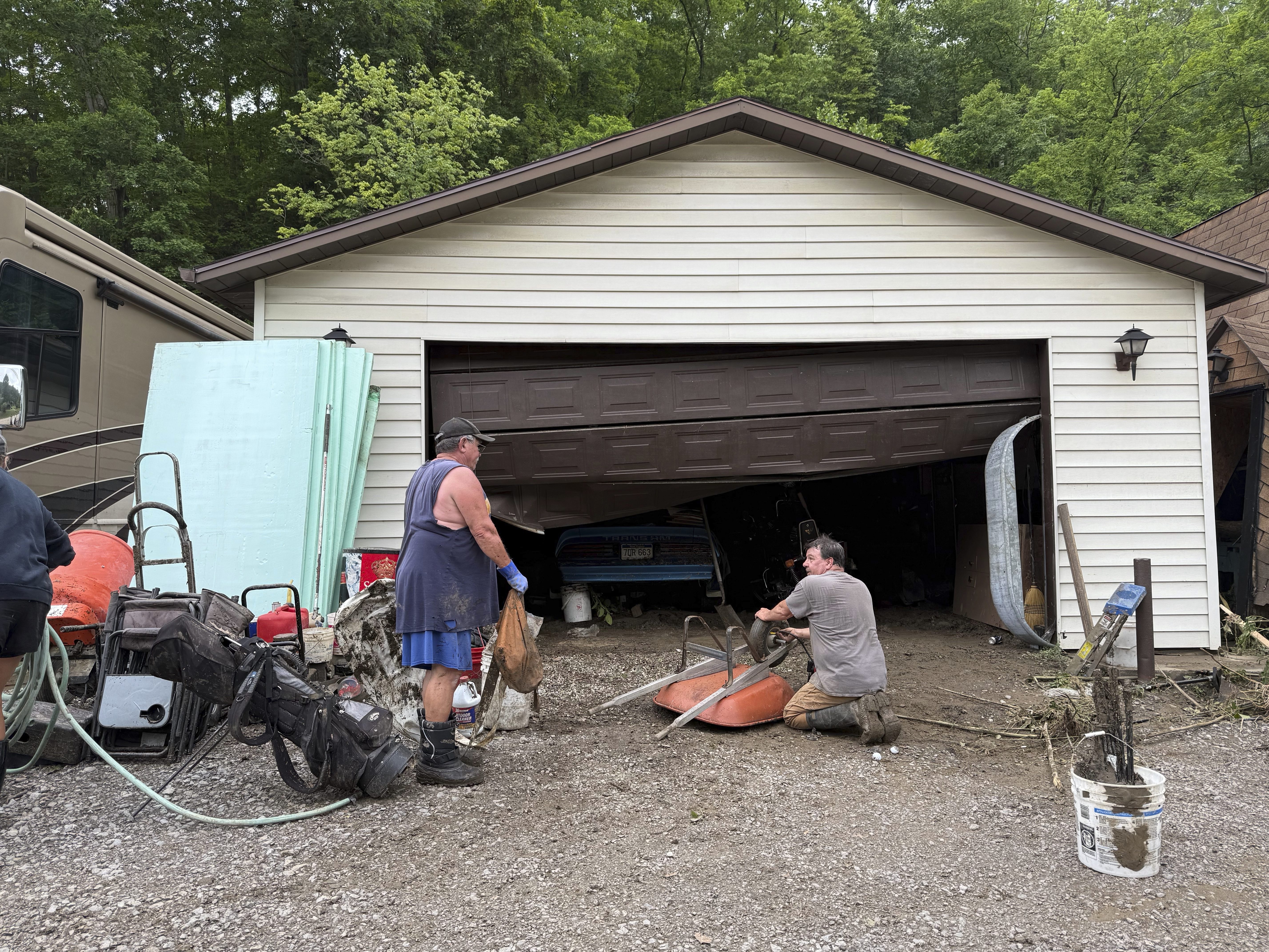 Chuck Ullom, left, and Rich Templin clean up Templin's damaged property after floods swept through the area on Monday, June 16, 2025 in Tridelphia, W.Va. (AP Photo/Patrick Aftoora-Orsagos)