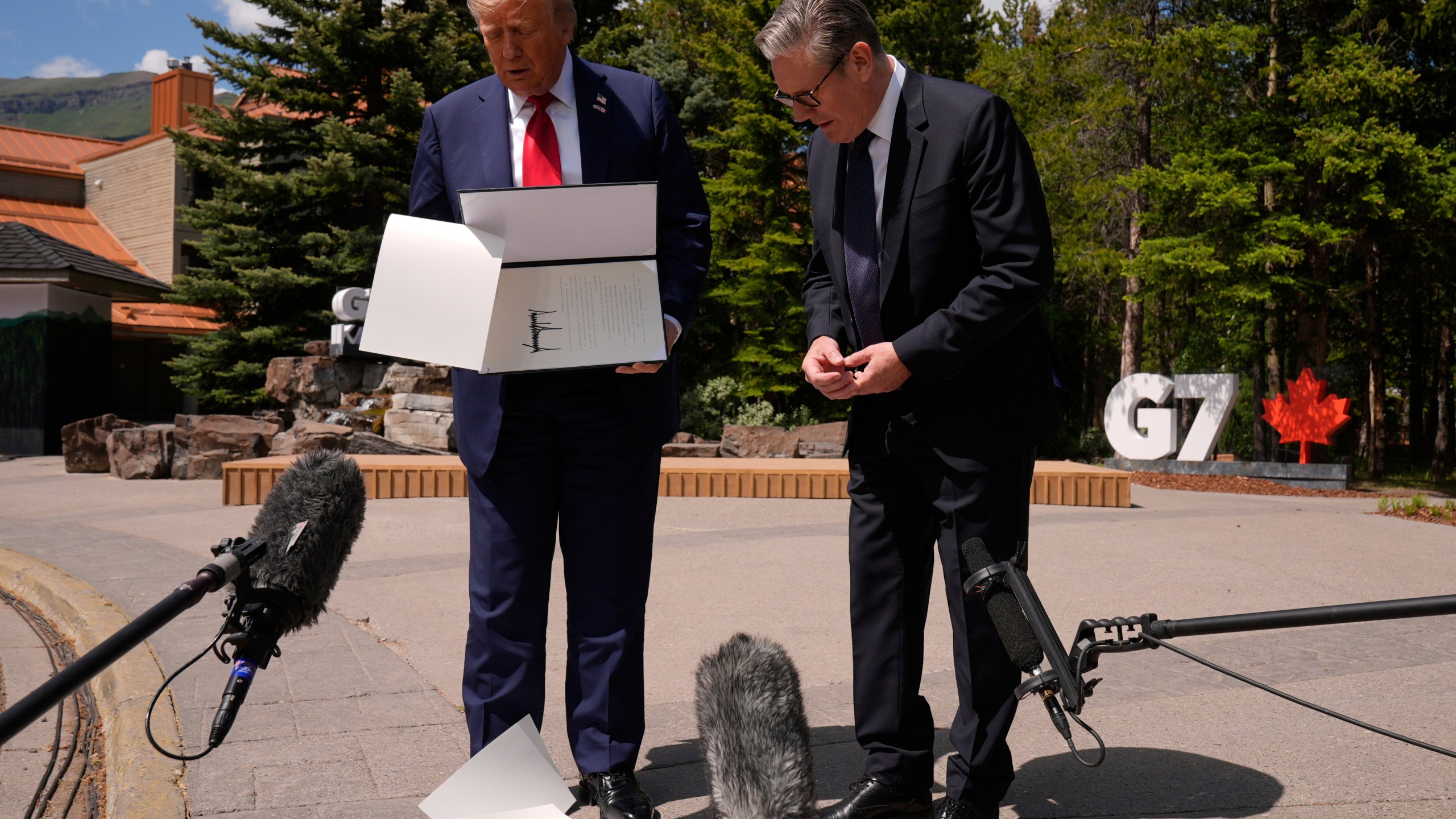 President Donald Trump drops papers as he meets with Britain's Prime Minister Keir Starmer on the sidelines of the G7 Summit, Monday, June 16, 2025, in Kananaskis, Canada. (AP Photo/Mark Schiefelbein)