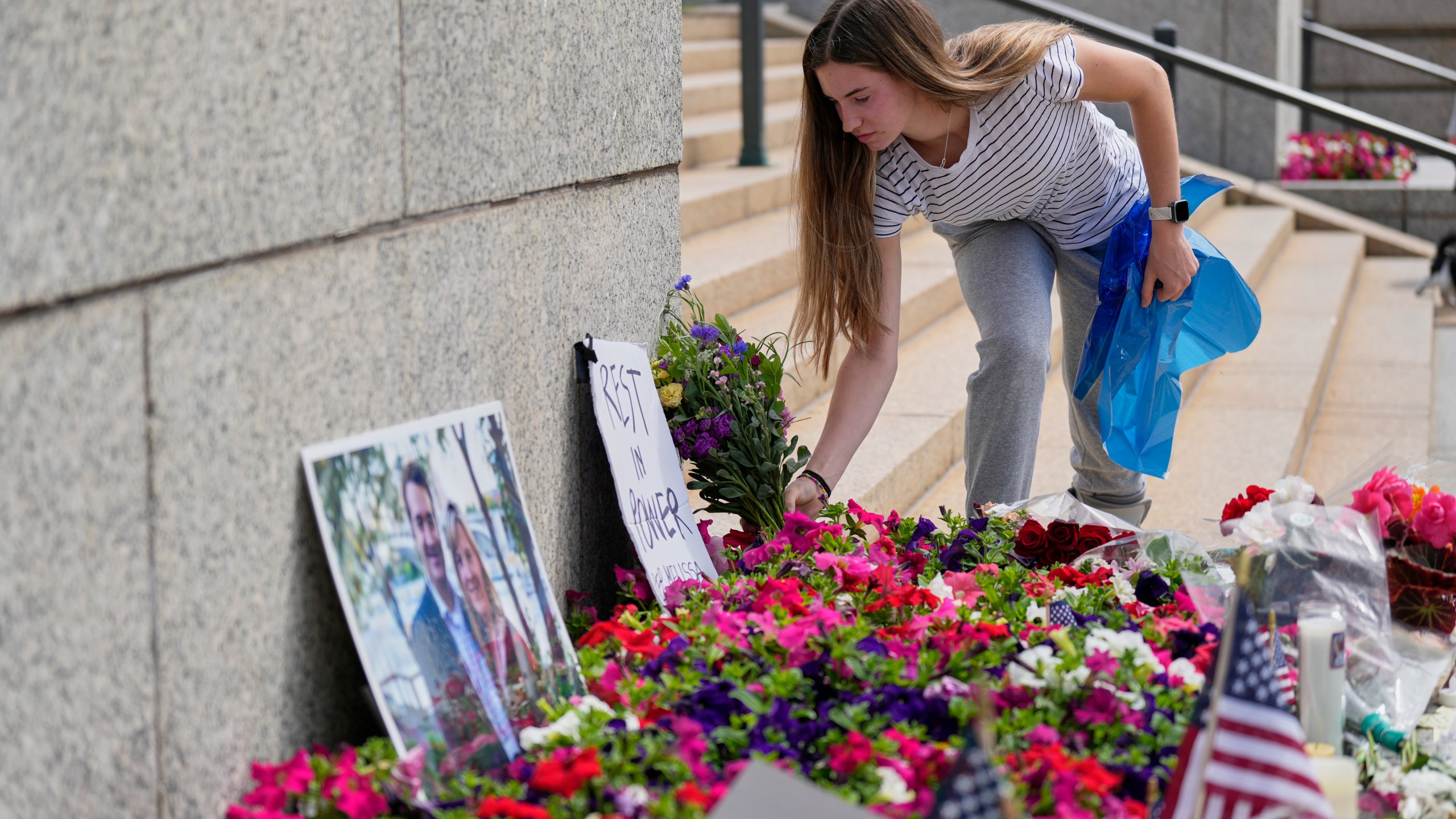 Claire Stein places flowers at a makeshift memorial for Minnesota state Rep. Melissa Hortman and her husband Mark at the state Capitol, Sunday, June 15, 2025, in St. Paul, Minn. (AP Photo/George Walker IV)