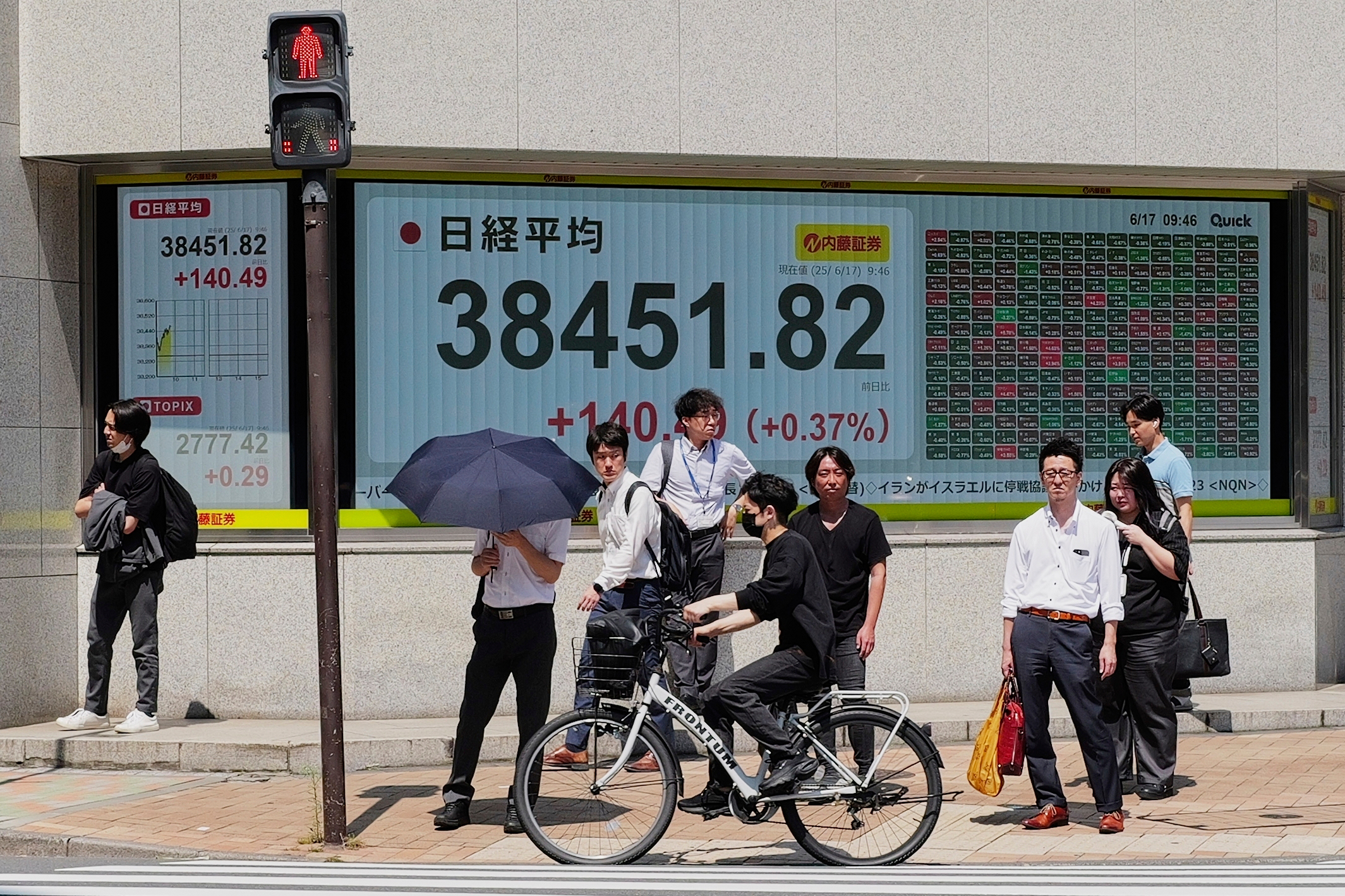 People stand in front of an electronic stock board showing Japan's Nikkei index at a securities firm Tuesday, June 17, 2025, in Tokyo. (AP Photo/Eugene Hoshiko)