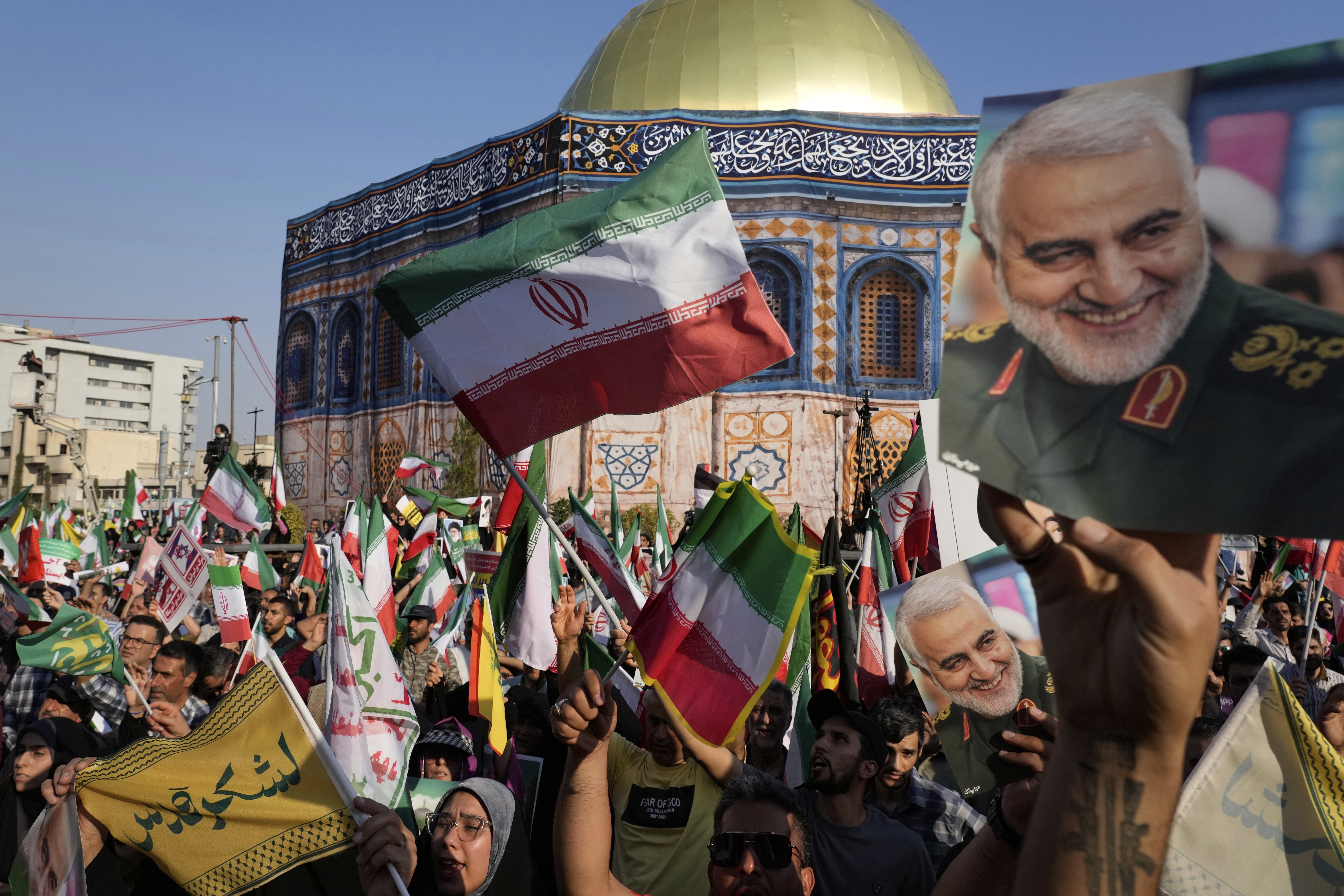 Demonstrators wave Iranian flags and hold posters of the late Iranian Revolutionary Guard Gen. Qassem Soleimani, who was killed in a U.S. strike in Iraq in 2020, in front of a model of Jerusalem's Dome of the Rock mosque during a rally marking the Muslim Shiite holiday of Eid al-Ghadir, which commemorates the Prophet Muhammad naming his successor, Ali, who is revered as the first Shiite imam, in Tehran, Iran, Saturday, June 14, 2025. (AP Photo/Vahid Salemi)