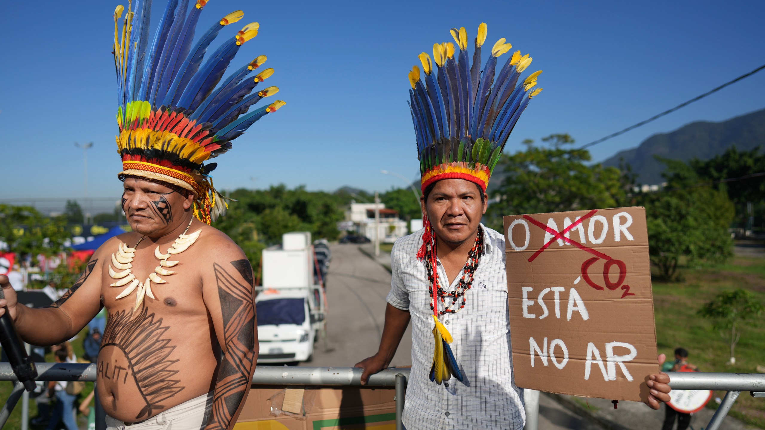 Indigenous demonstrators holds a sign that reads in Portuguese "Love, CO2 is in the air" to protest the auction of dozens of oil blocks, including blocks near the mouth of the Amazon River, in Rio de Janeiro, Tuesday, June 17, 2025. (AP Photo/Silvia Izquierdo)