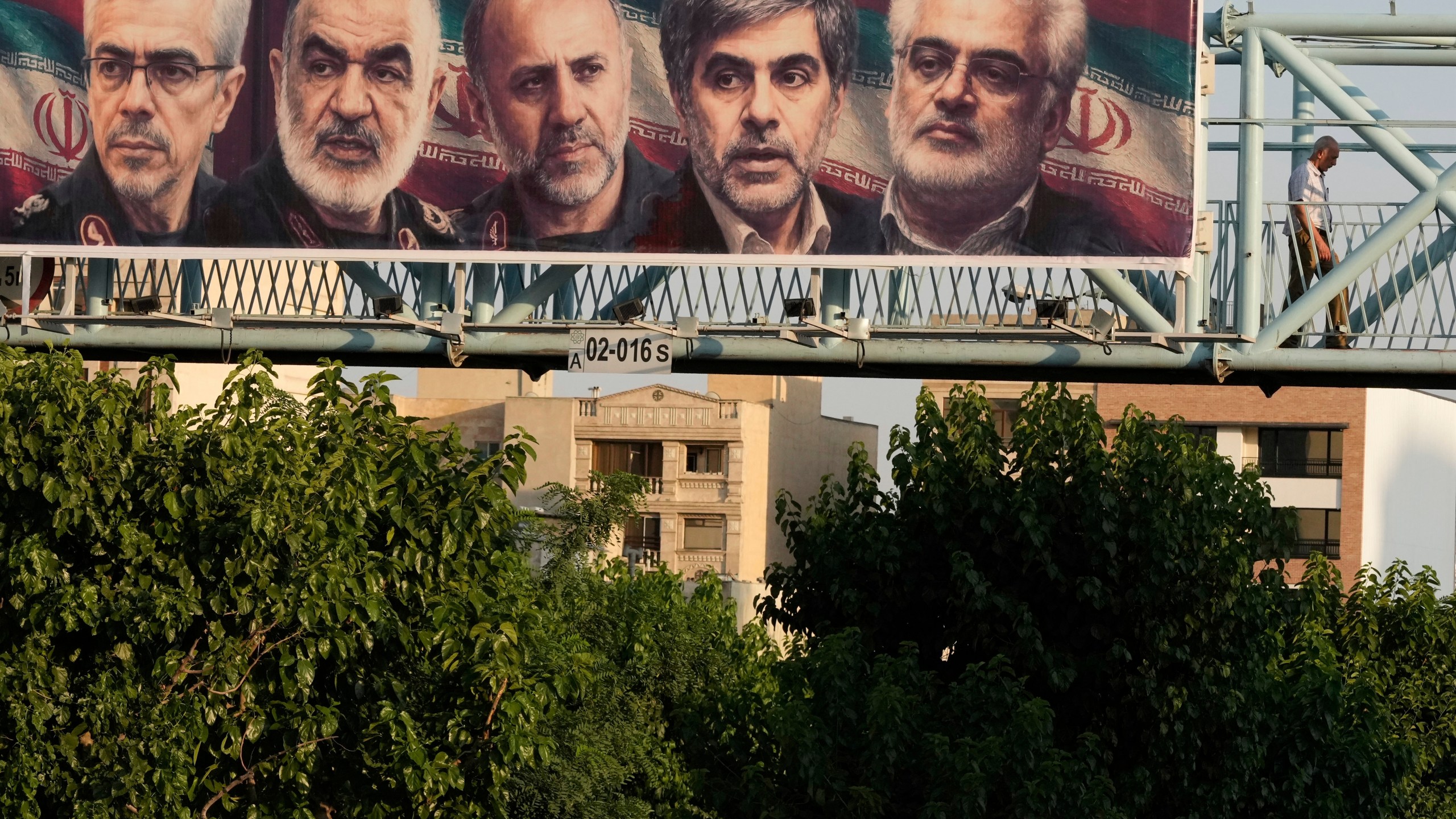 A man walks past a billboard displaying images of top Iranian commanders and scientists killed in Israeli strikes early Friday, in Tehran, Iran, Friday, June 13, 2025. (AP Photo/Vahid Salemi)