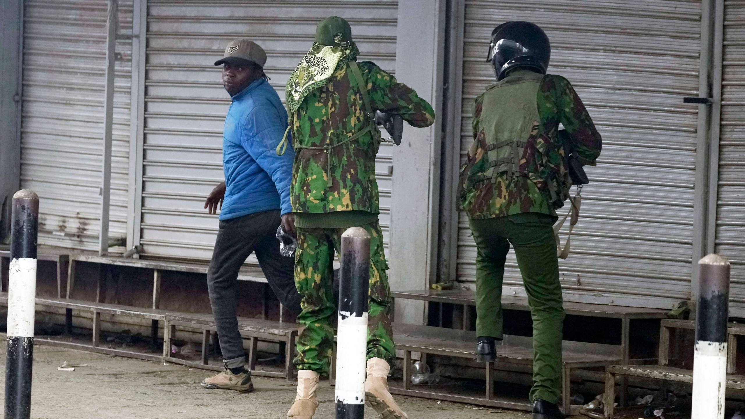 A Kenyan policeman, center, prepares to shoot a man who appeared to be a vendor, left, during a protest in Nairobi, Kenya, Tuesday, June 17, 2025. (AP Photo/Brian Inganga)