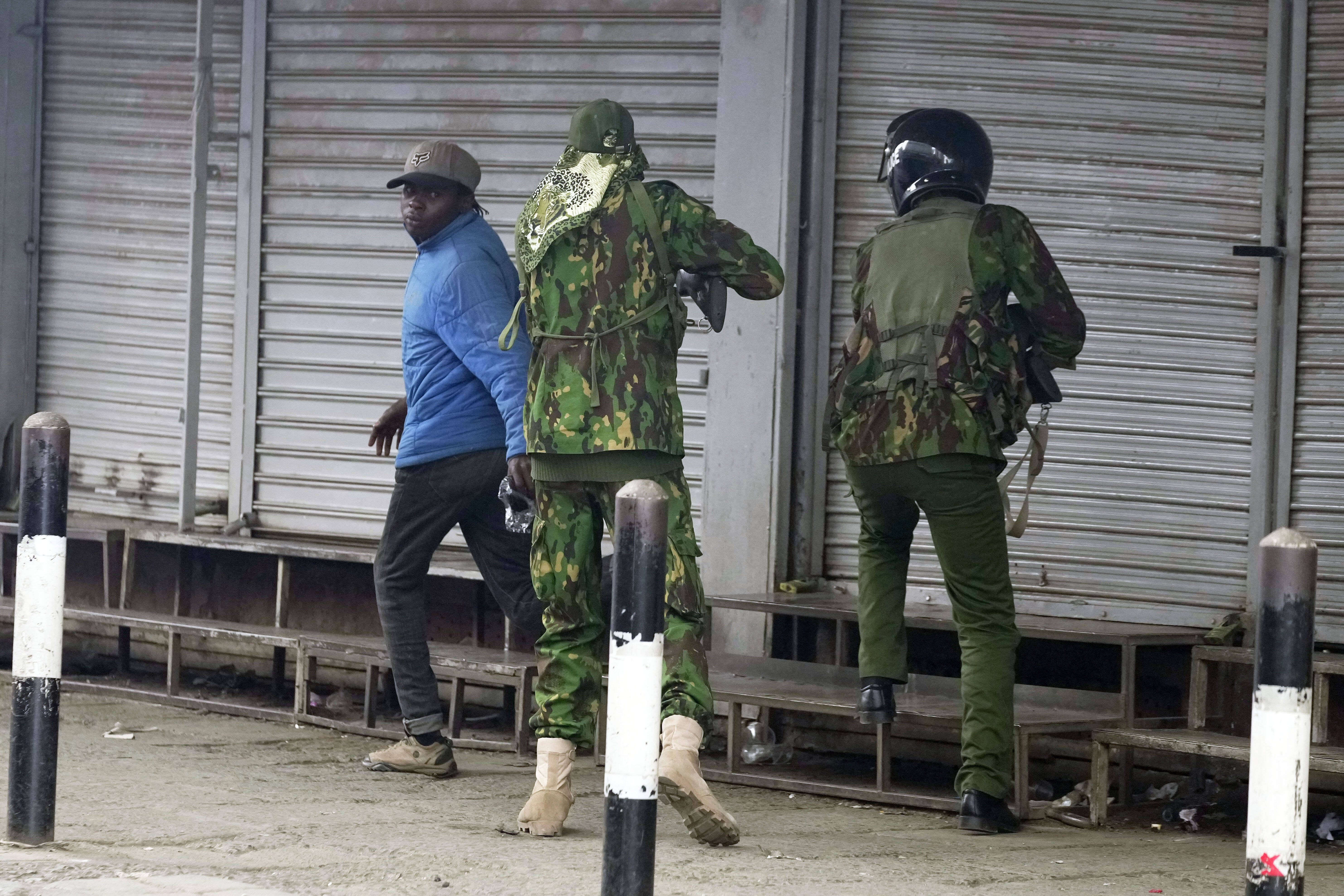 A Kenyan policeman, center, prepares to shoot a man who appeared to be a vendor, left, during a protest in Nairobi, Kenya, Tuesday, June 17, 2025. (AP Photo/Brian Inganga)