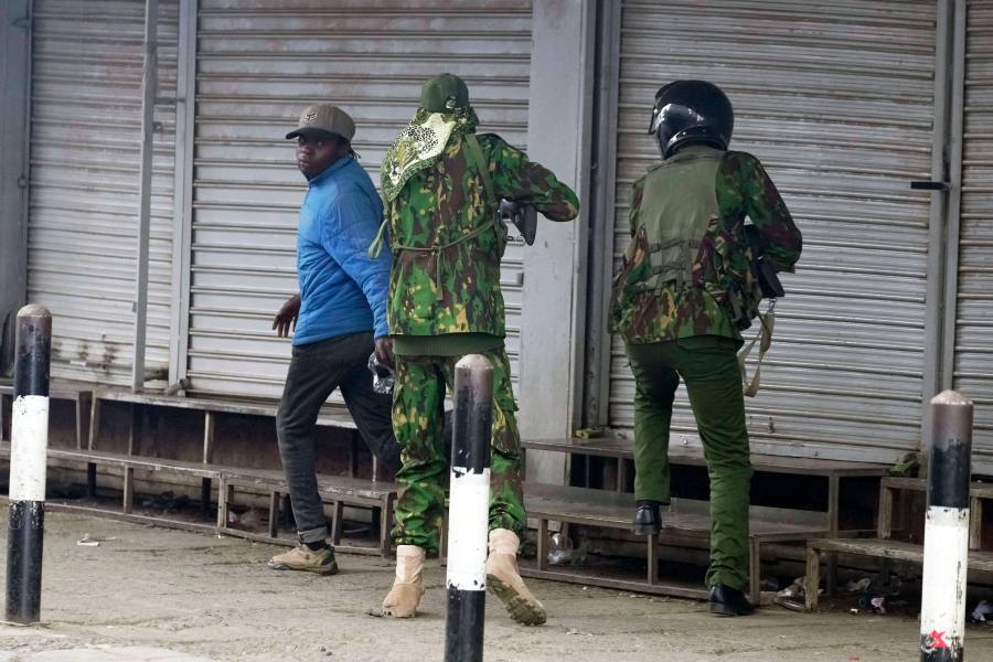 A Kenyan policeman, center, prepares to shoot a man who appeared to be a vendor, left, during a protest in Nairobi, Kenya, Tuesday, June 17, 2025. (AP Photo/Brian Inganga)