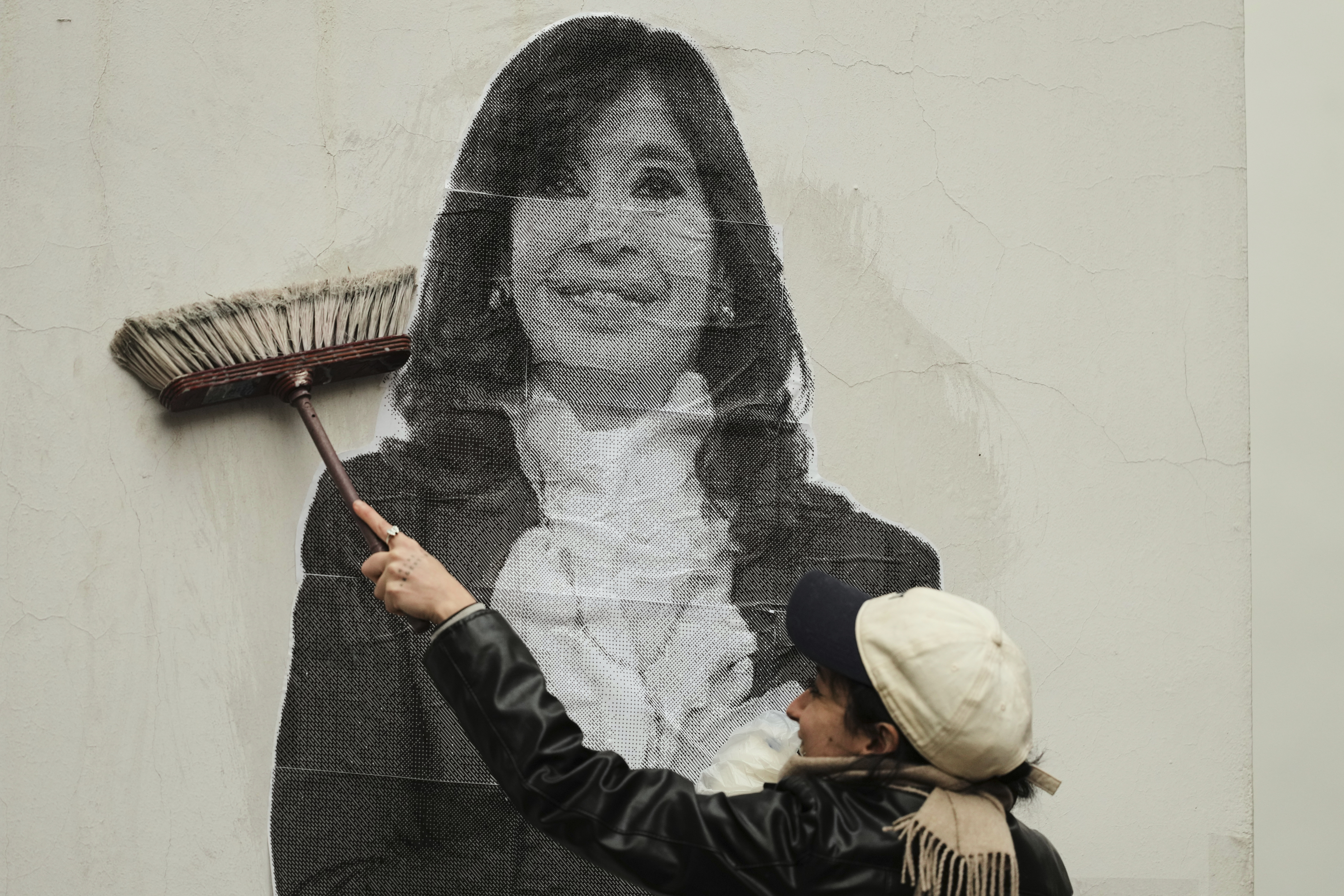 A supporter of Argentina's former President Cristina Fernandez uses a boom to paste a photo of her on the wall outside her home after the nation's Supreme Court upheld Fernandez's corruption conviction in Buenos Aires, Argentina, Tuesday, June 17, 2025. (AP Photo/Natacha Pisarenko)