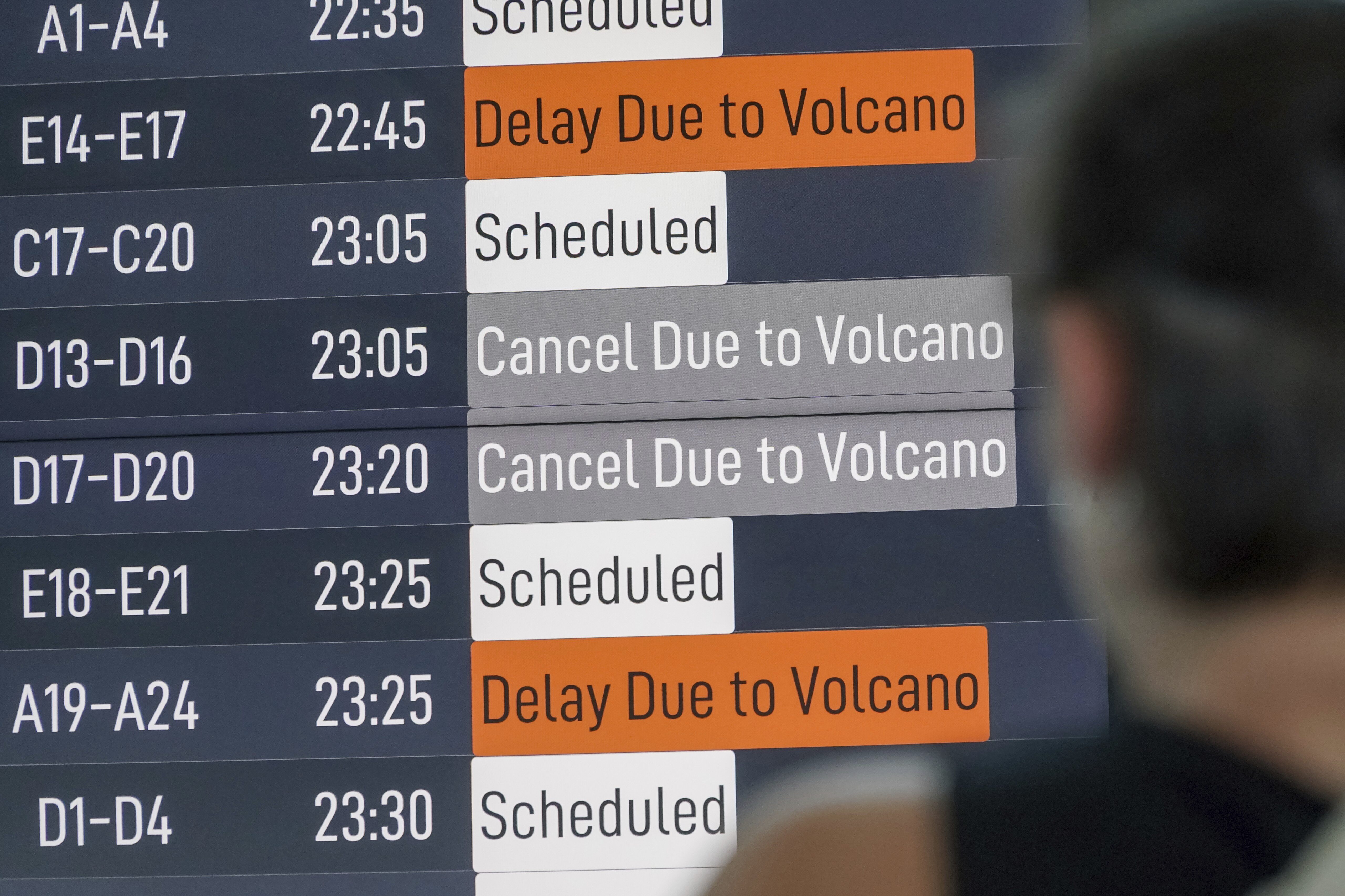 A passenger checks an information board showing disrupted flight schedule due to the eruption of Mount Lewotobi Laki-Laki, at Ngurah Rai International Airport in Badung, Bali, Indonesia, Wednesday, June 18, 2025. (AP Photo/Herdyanto)