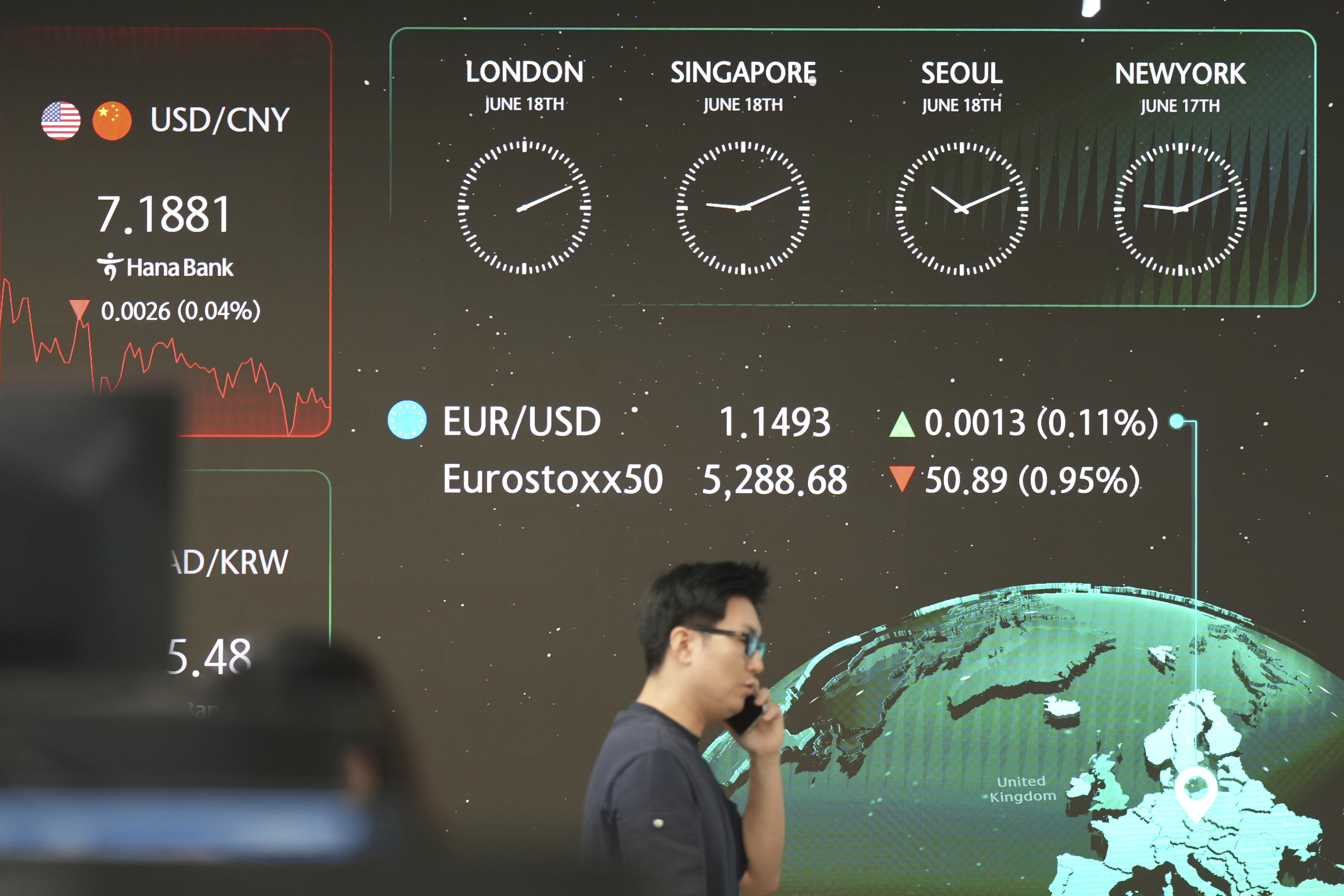 A dealer walks past near the screens showing the foreign exchange rates at a dealing room of Hana Bank in Seoul, South Korea, Wednesday, June 18, 2025. (AP Photo/Lee Jin-man)