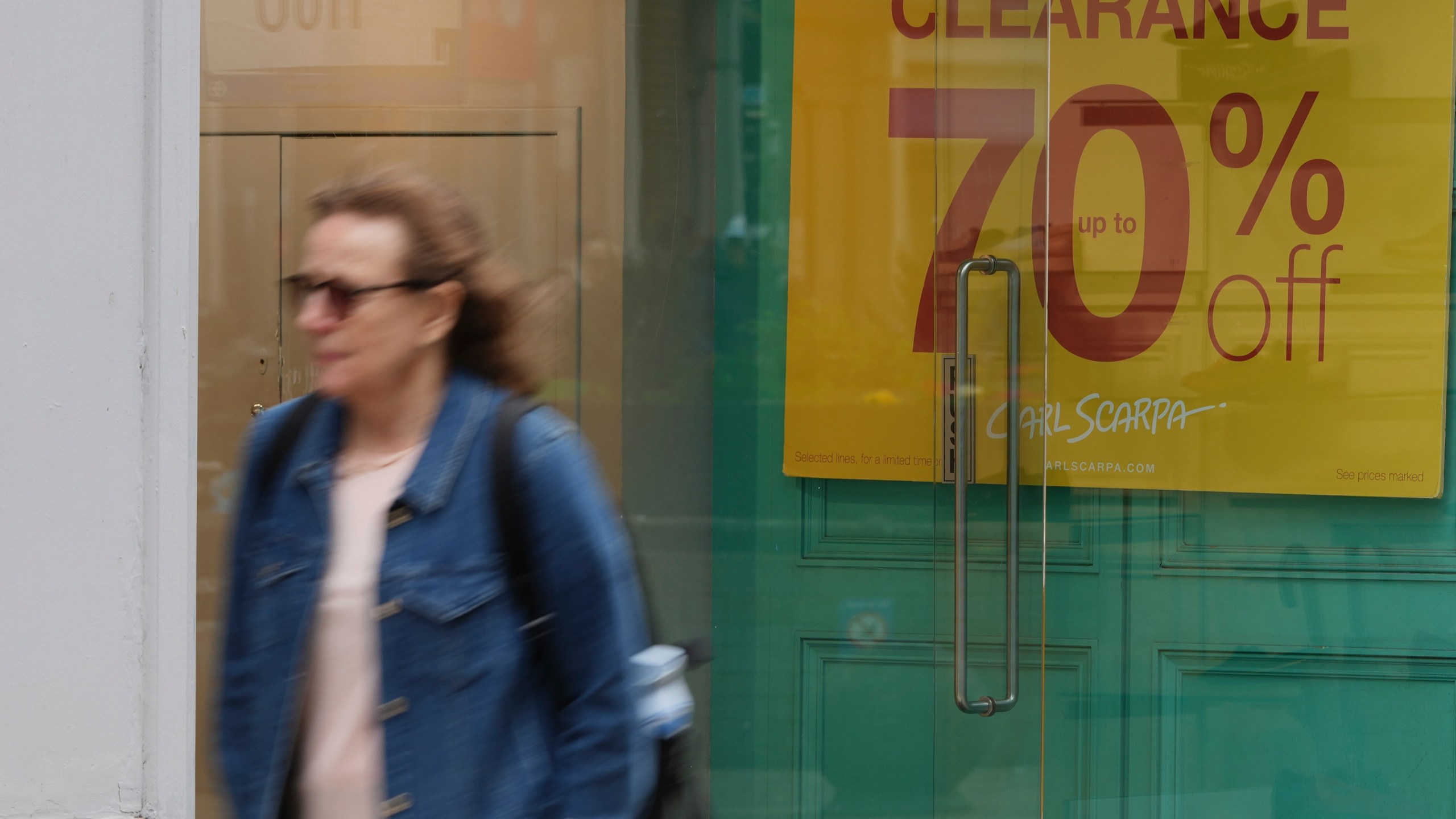 FILE - A woman walks past a shop offering a clearance sale in Richmond southwest London, Thursday, March 27, 2025. (AP Photo/Alastair Grant, File)