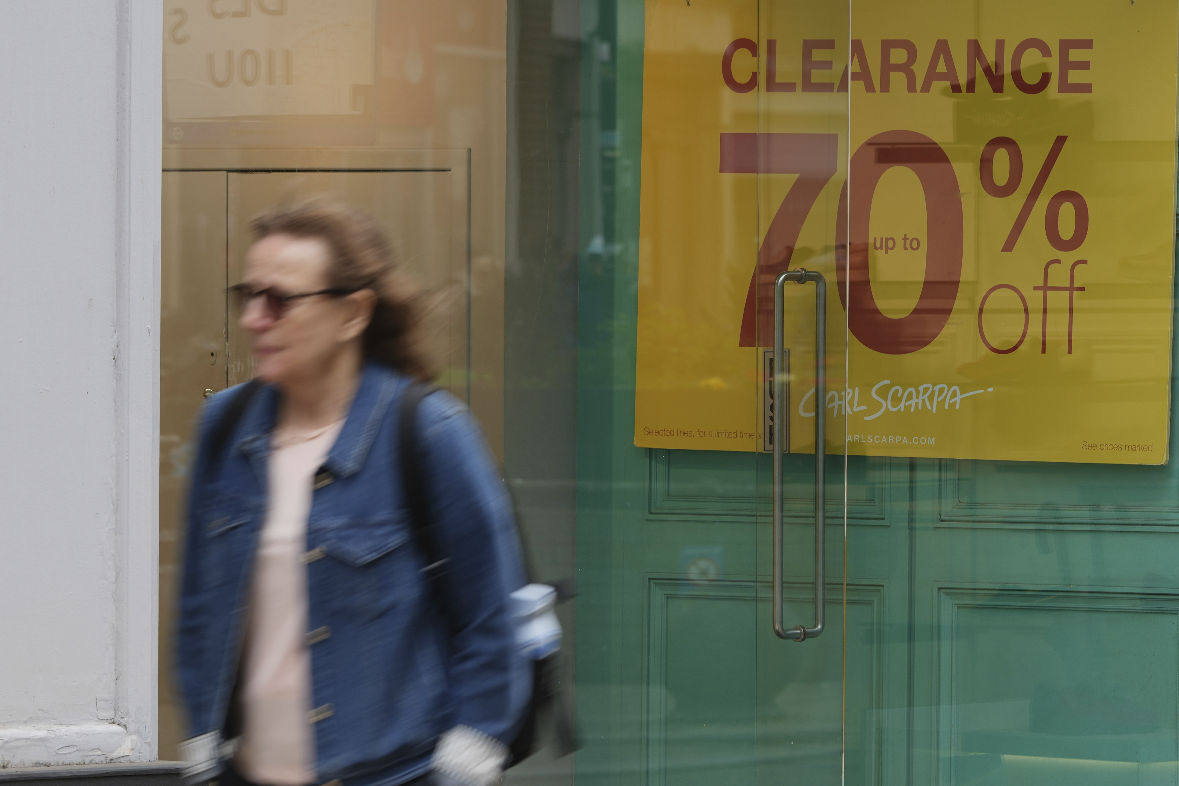 FILE - A woman walks past a shop offering a clearance sale in Richmond southwest London, Thursday, March 27, 2025. (AP Photo/Alastair Grant, File)
