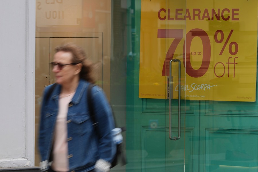 FILE - A woman walks past a shop offering a clearance sale in Richmond southwest London, Thursday, March 27, 2025. (AP Photo/Alastair Grant, File)