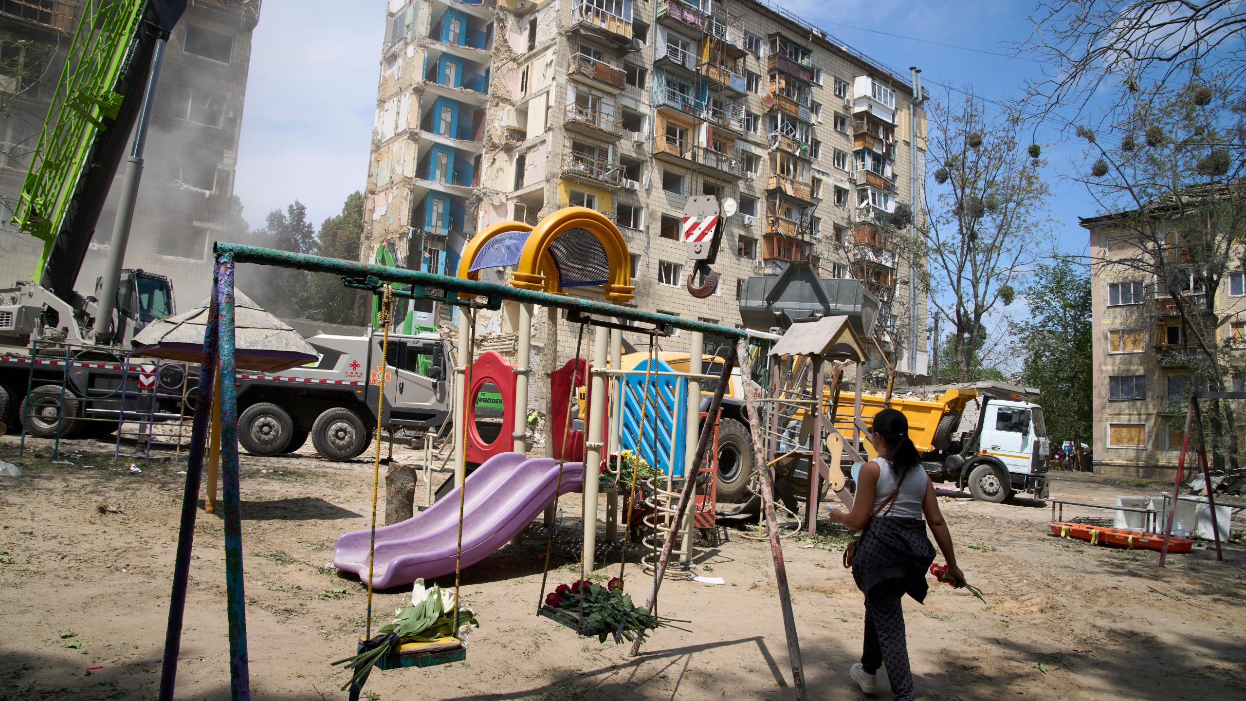 A woman lays flowers at the site of Russia's Tuesday deadly missile attack that ruined a multistory residential building in Kyiv, Ukraine, Wednesday, June 18, 2025. (AP Photo/Efrem Lukatsky)