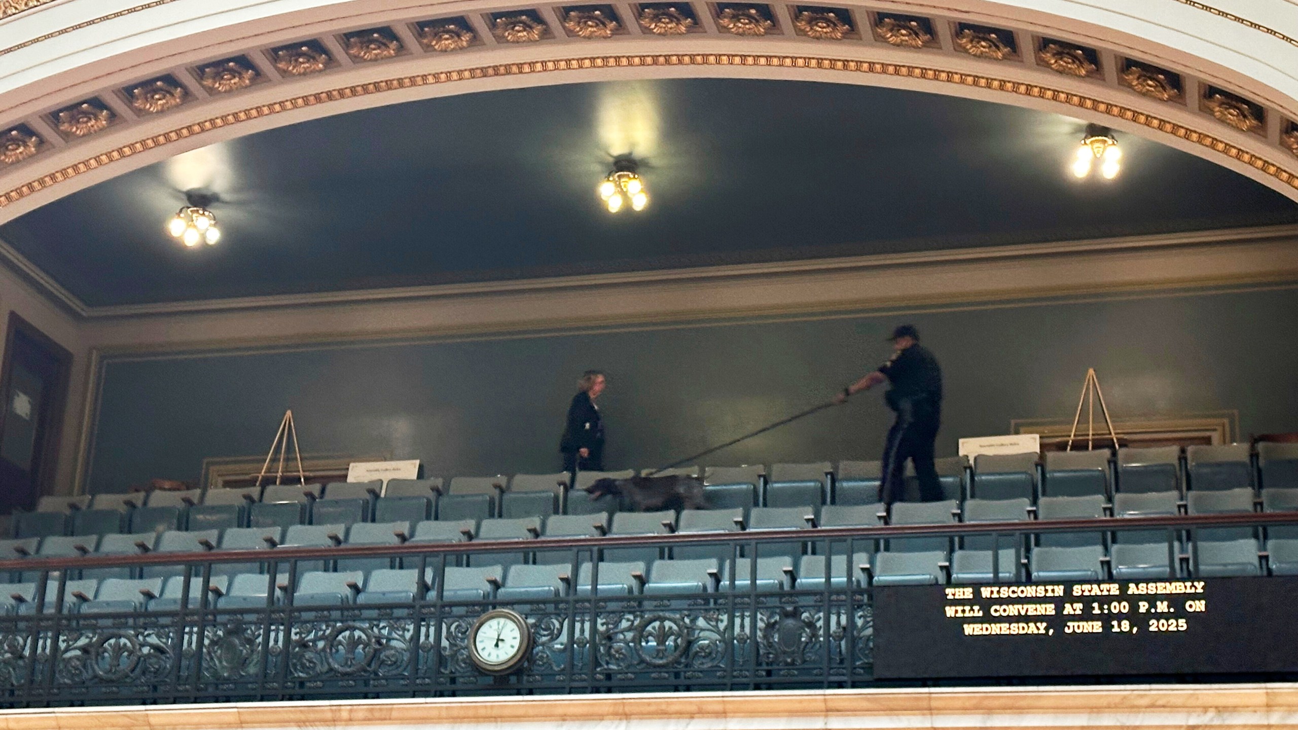 A police officer with a bomb-sniffing dog scans the public viewing gallery inside the Wisconsin state Assembly chamber, Wednesday, June 18, 2025, in Madison, Wis., a sign of increased security following the killing of a lawmaker in neighboring Minnesota. (AP Photo/Scott Bauer)