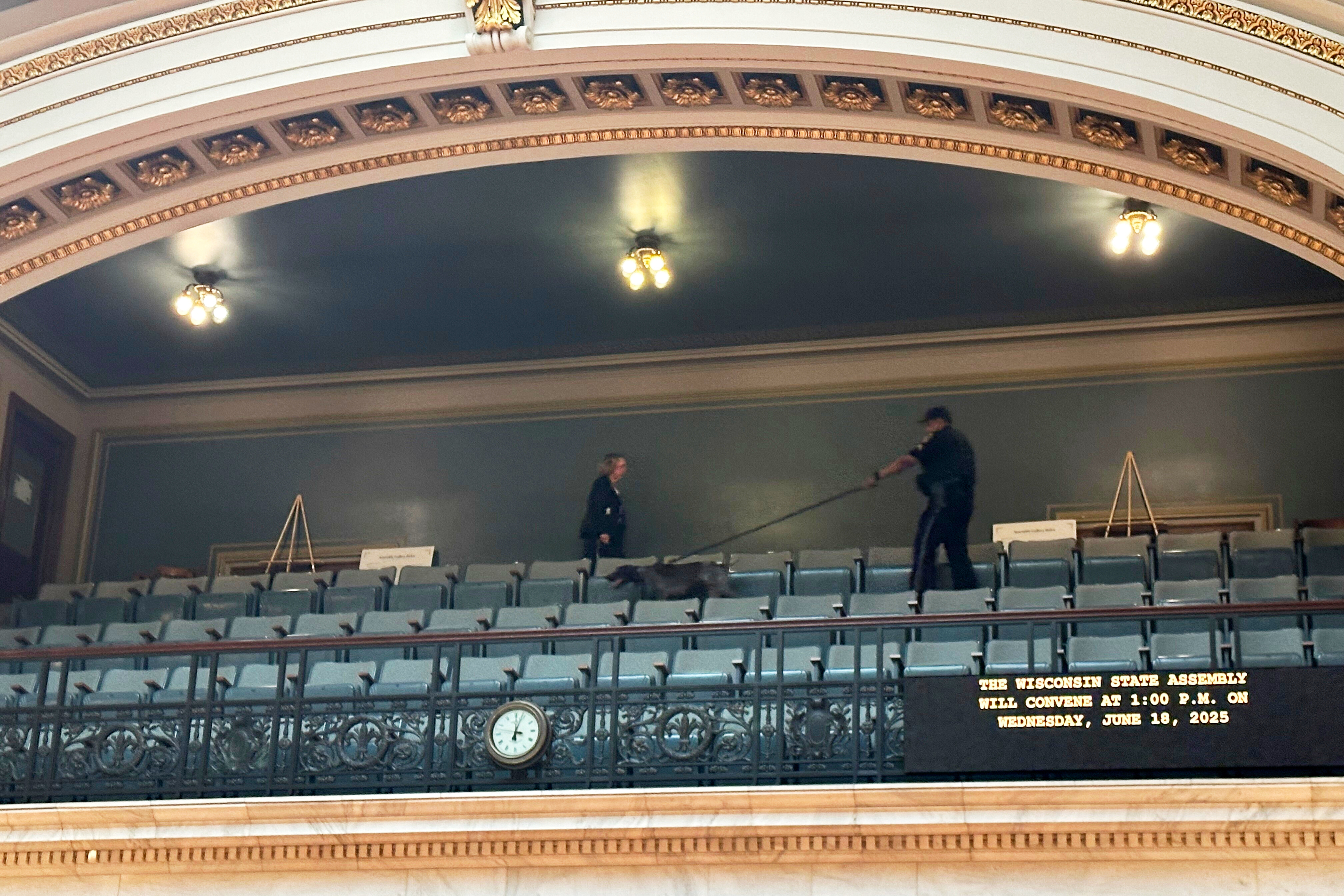 A police officer with a bomb-sniffing dog scans the public viewing gallery inside the Wisconsin state Assembly chamber, Wednesday, June 18, 2025, in Madison, Wis., a sign of increased security following the killing of a lawmaker in neighboring Minnesota. (AP Photo/Scott Bauer)