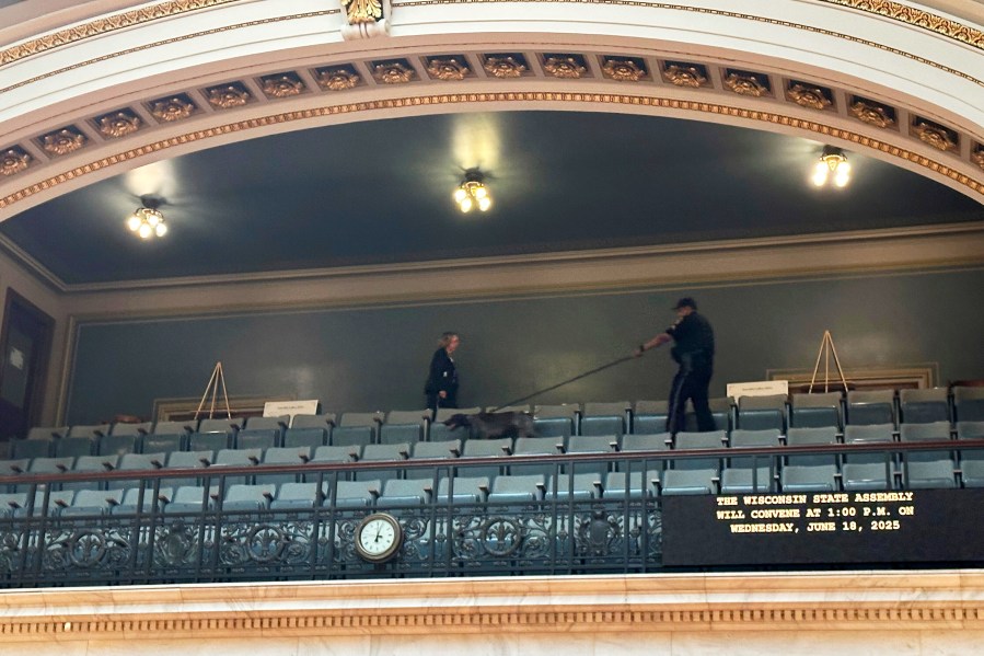 A police officer with a bomb-sniffing dog scans the public viewing gallery inside the Wisconsin state Assembly chamber, Wednesday, June 18, 2025, in Madison, Wis., a sign of increased security following the killing of a lawmaker in neighboring Minnesota. (AP Photo/Scott Bauer)