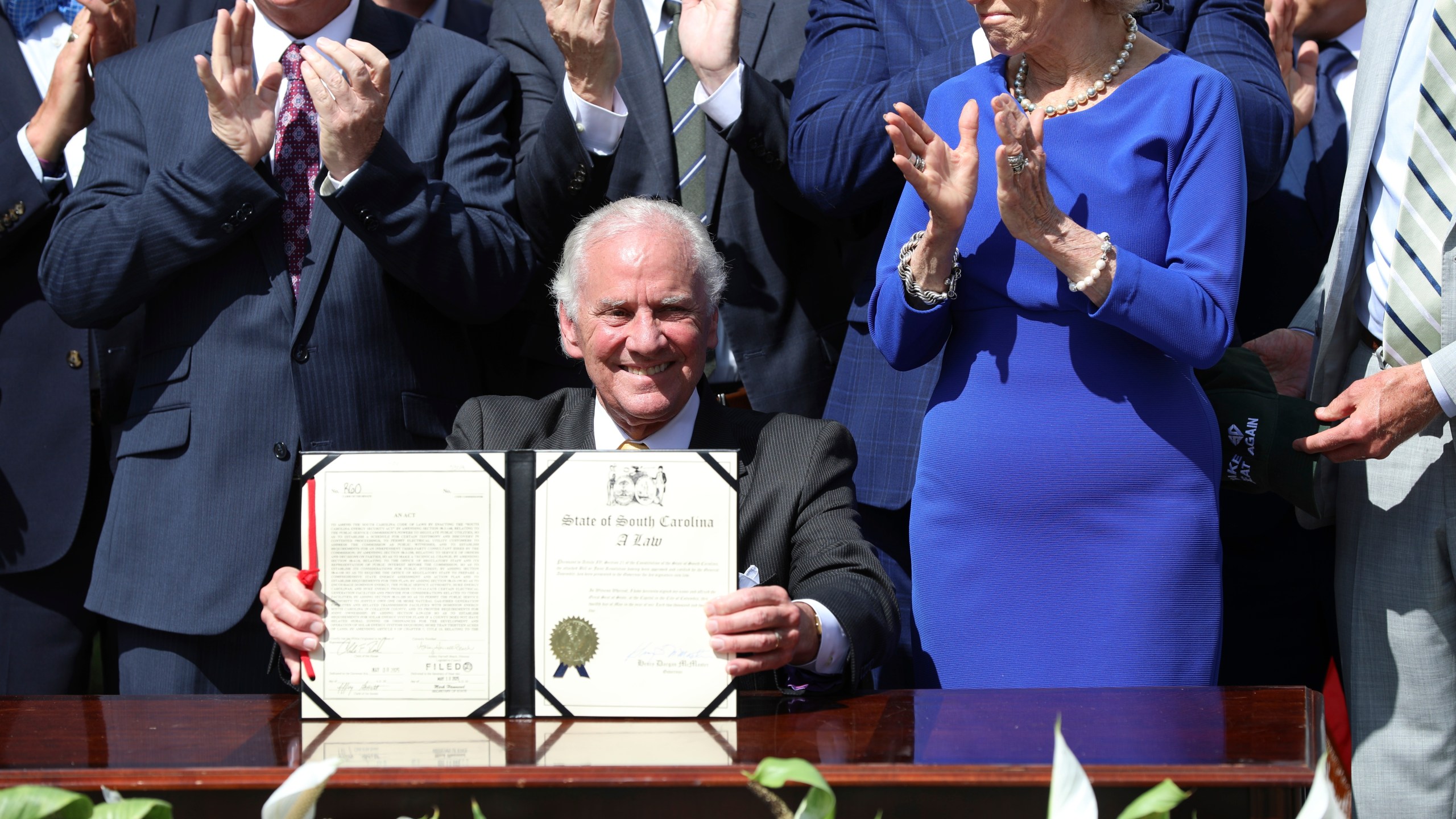 Republican South Carolina Gov. Henry McMaster holds up a ceremonial copy of a bill he signed changing South Carolina's energy laws on Wednesday, June 18, 2025, in Columbia, S.C. (AP Photo/Jeffrey Collins)