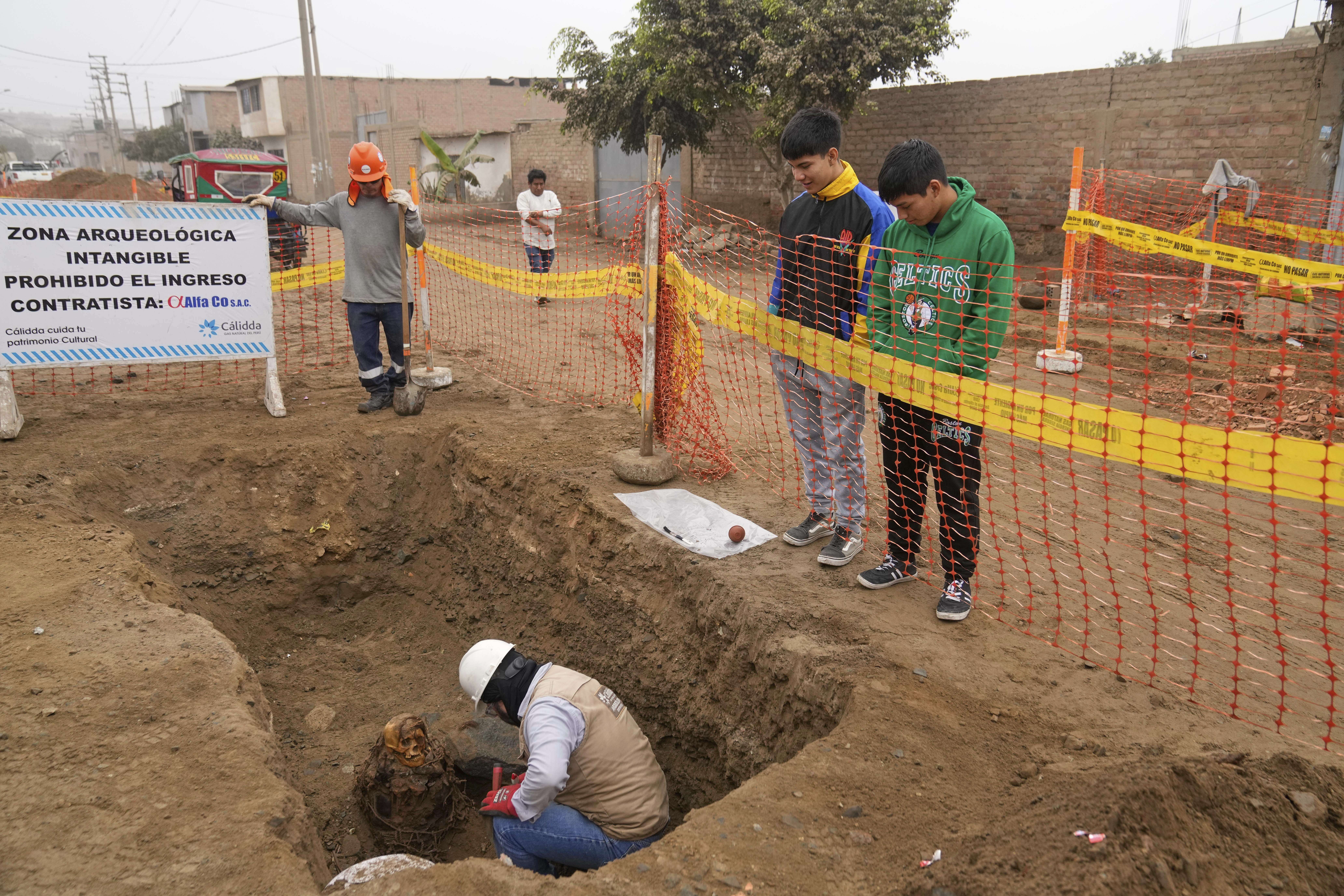 Archaeologist Jose Aliaga excavates an ancient mummy, which he said is a female from the pre-Inca Chancay culture, that was discovered by city workers who were digging a natural gas line for the company Calidda in the district of Puente Piedra on the outskirts of Lima, Peru, Wednesday, June 18, 2025. (AP Photo/Martin Mejia)