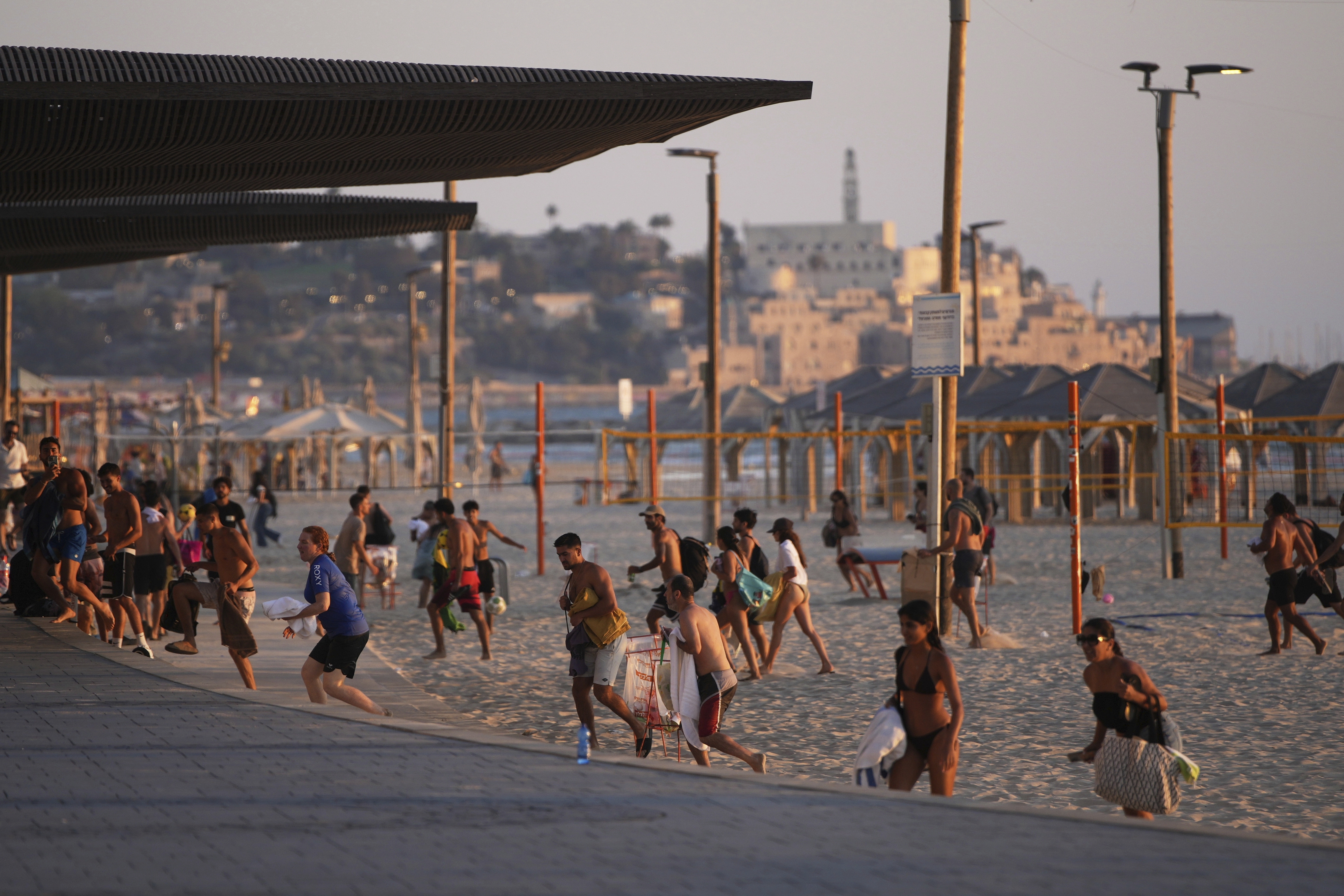 Beachgoers leave during a missile alert from Iran, in Tel Aviv, Israel, Wednesday, June 18, 2025. (AP Photo/Ohad Zwigenberg)