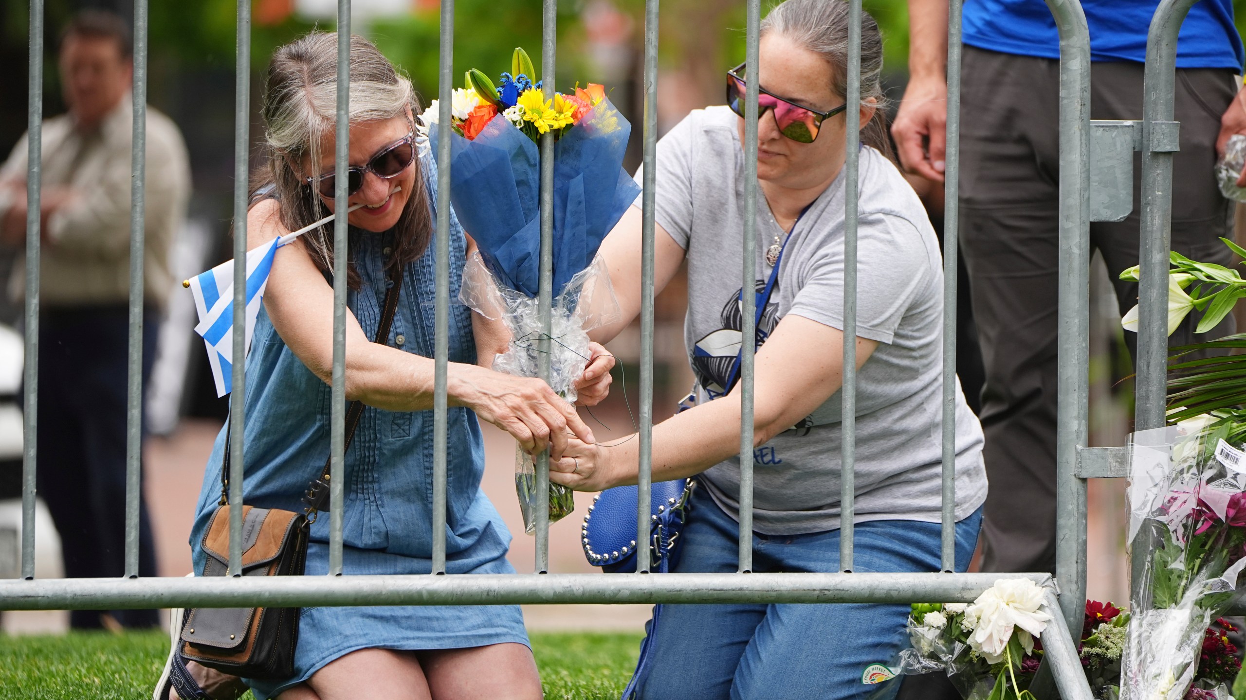 From left, Lisa Turnquist and Carrie Spyva-McIlvaine place a bouquet of flowers at a growing memorial outside of the Boulder County, Colo., courthouse after Sunday's attack Monday, June 2, 2025, in Boulder, Colo. (AP Photo/David Zalubowski)