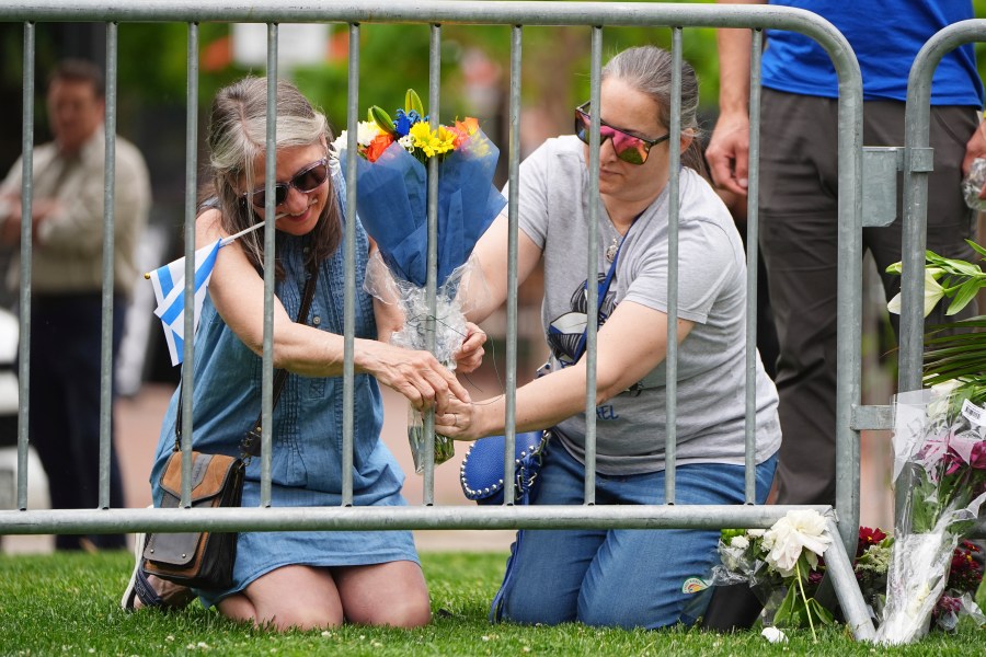 From left, Lisa Turnquist and Carrie Spyva-McIlvaine place a bouquet of flowers at a growing memorial outside of the Boulder County, Colo., courthouse after Sunday's attack Monday, June 2, 2025, in Boulder, Colo. (AP Photo/David Zalubowski)