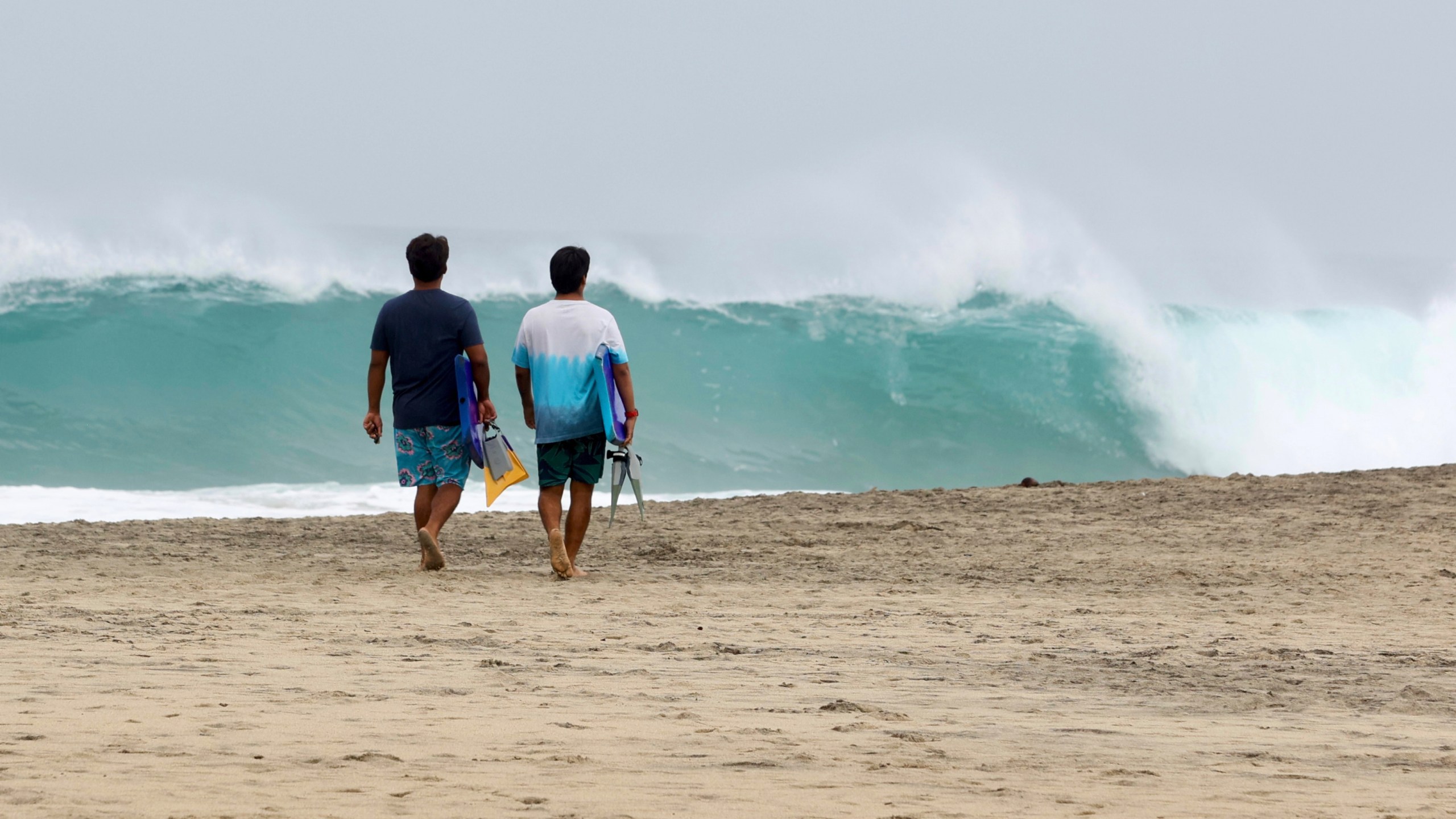 People walk on Zicatela beach prior to the arrival of Hurricane Erick in Puerto Escondido, Oaxaca state, Mexico, Wednesday, June 18, 2025. (AP Photo/Luis Alberto Cruz)