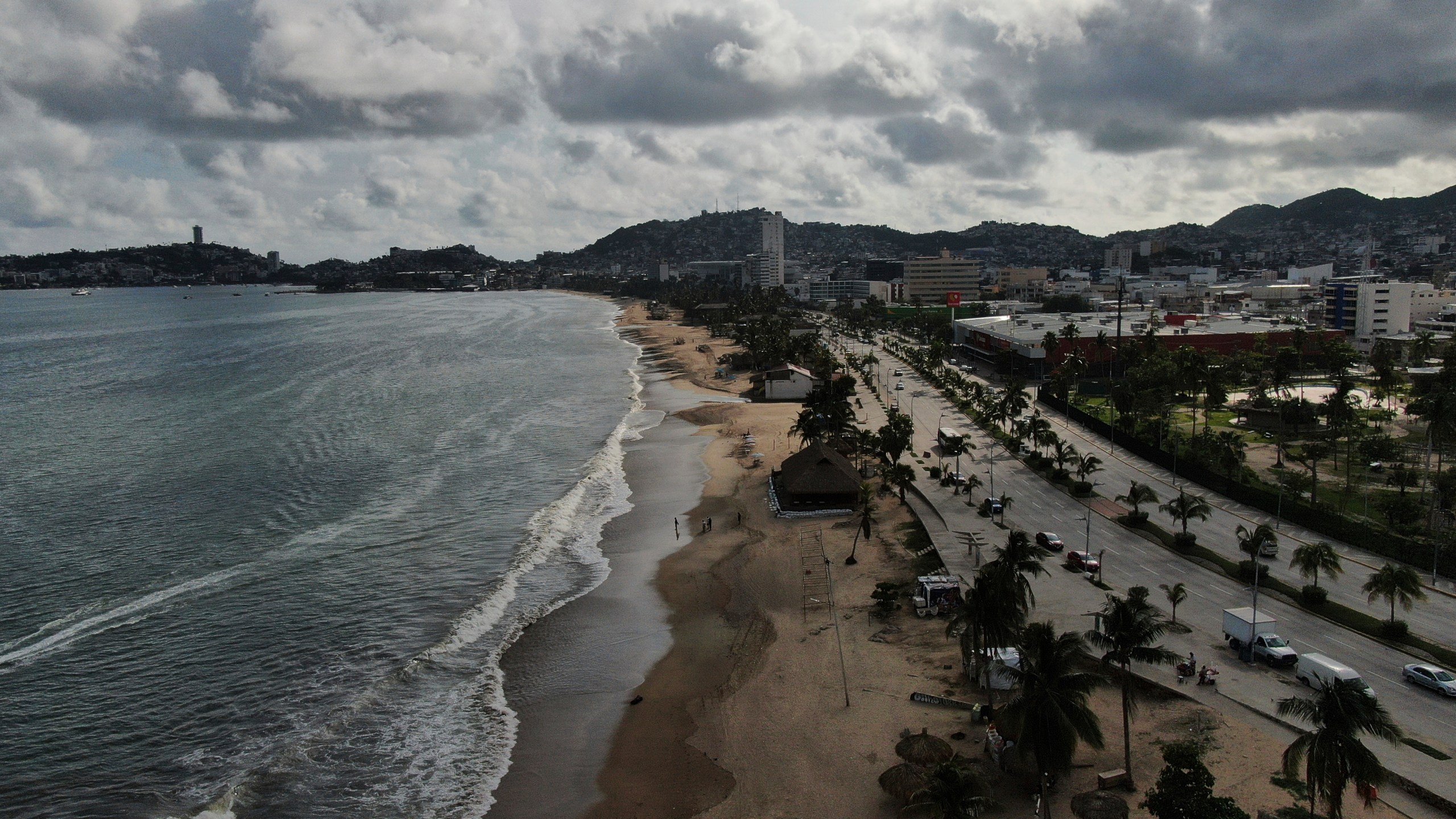 Tourists stroll along the beach shore before the arrival of Hurricane Erick, in Acapulco, Mexico, Wednesday, June 18, 2025. (AP Photo/Fernando Llano)