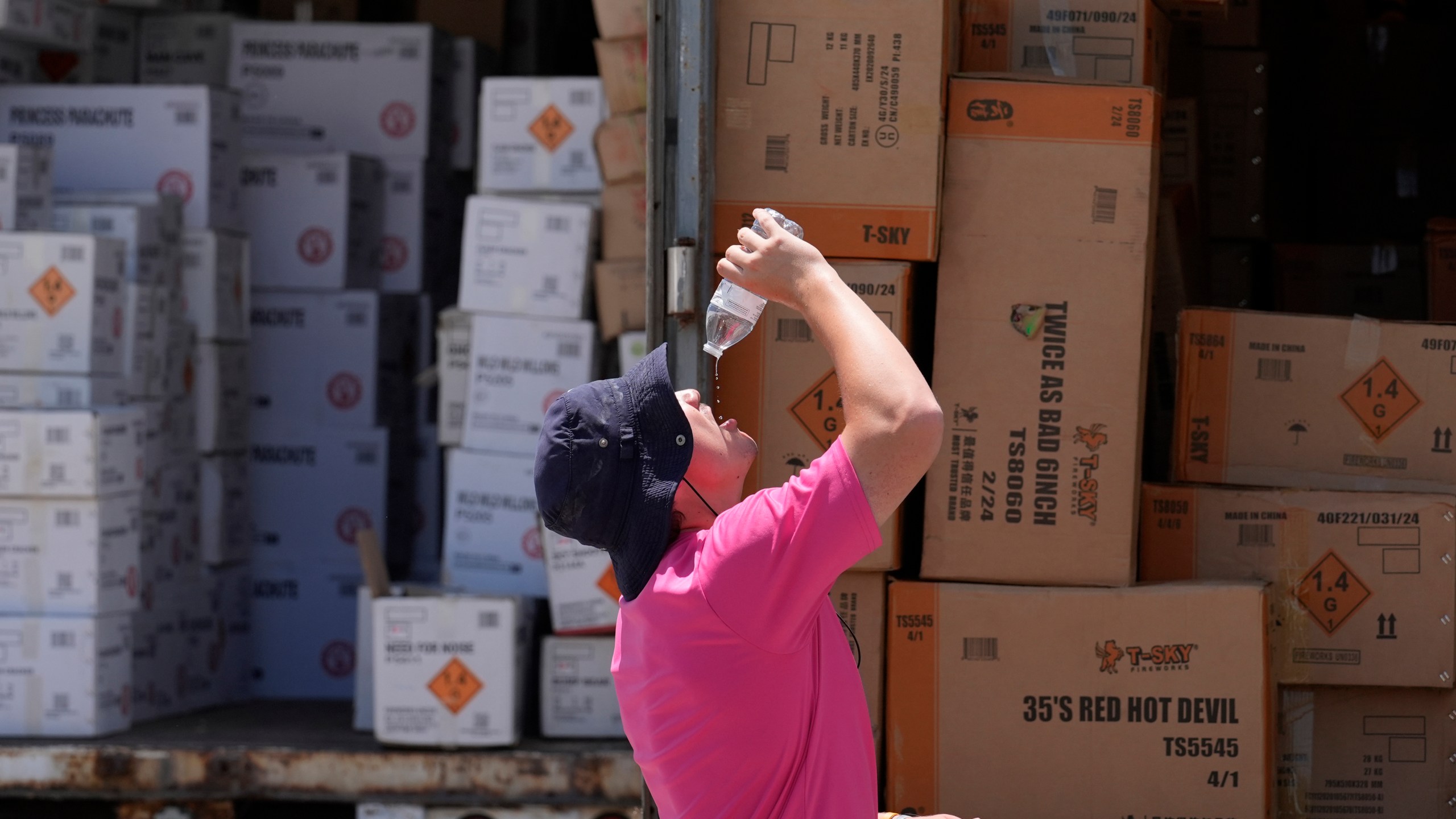 FILE - Wyatt Seymore pours the last drops of liquid from a water bottle into his mouth as he takes a break from unloading a stiflingly hot trailer of fireworks outside Powder Monkey Fireworks ahead of the opening of the stand, June 17, 2024, in Weldon Spring, Mo. (AP Photo/Jeff Roberson, File)