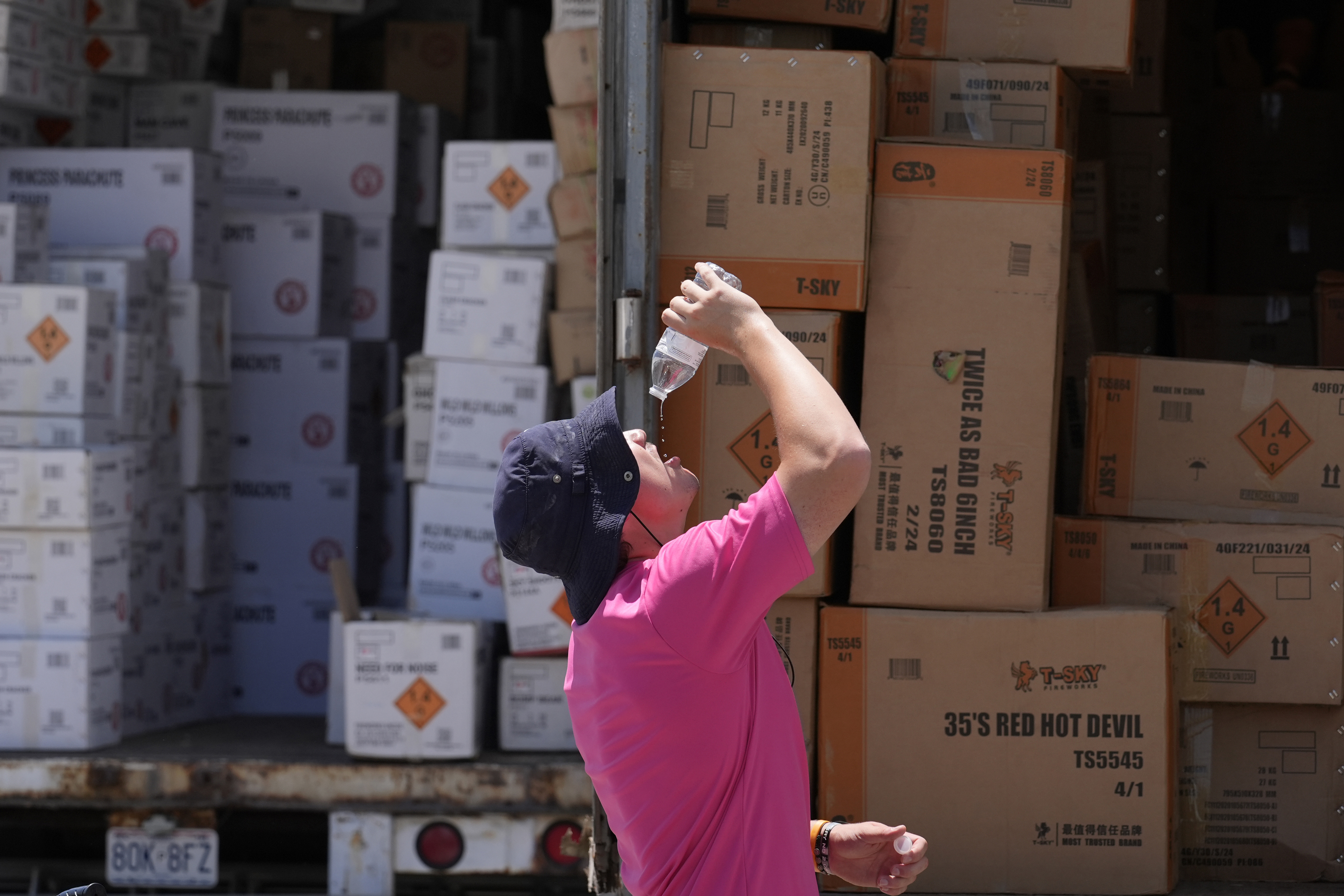 FILE - Wyatt Seymore pours the last drops of liquid from a water bottle into his mouth as he takes a break from unloading a stiflingly hot trailer of fireworks outside Powder Monkey Fireworks ahead of the opening of the stand, June 17, 2024, in Weldon Spring, Mo. (AP Photo/Jeff Roberson, File)