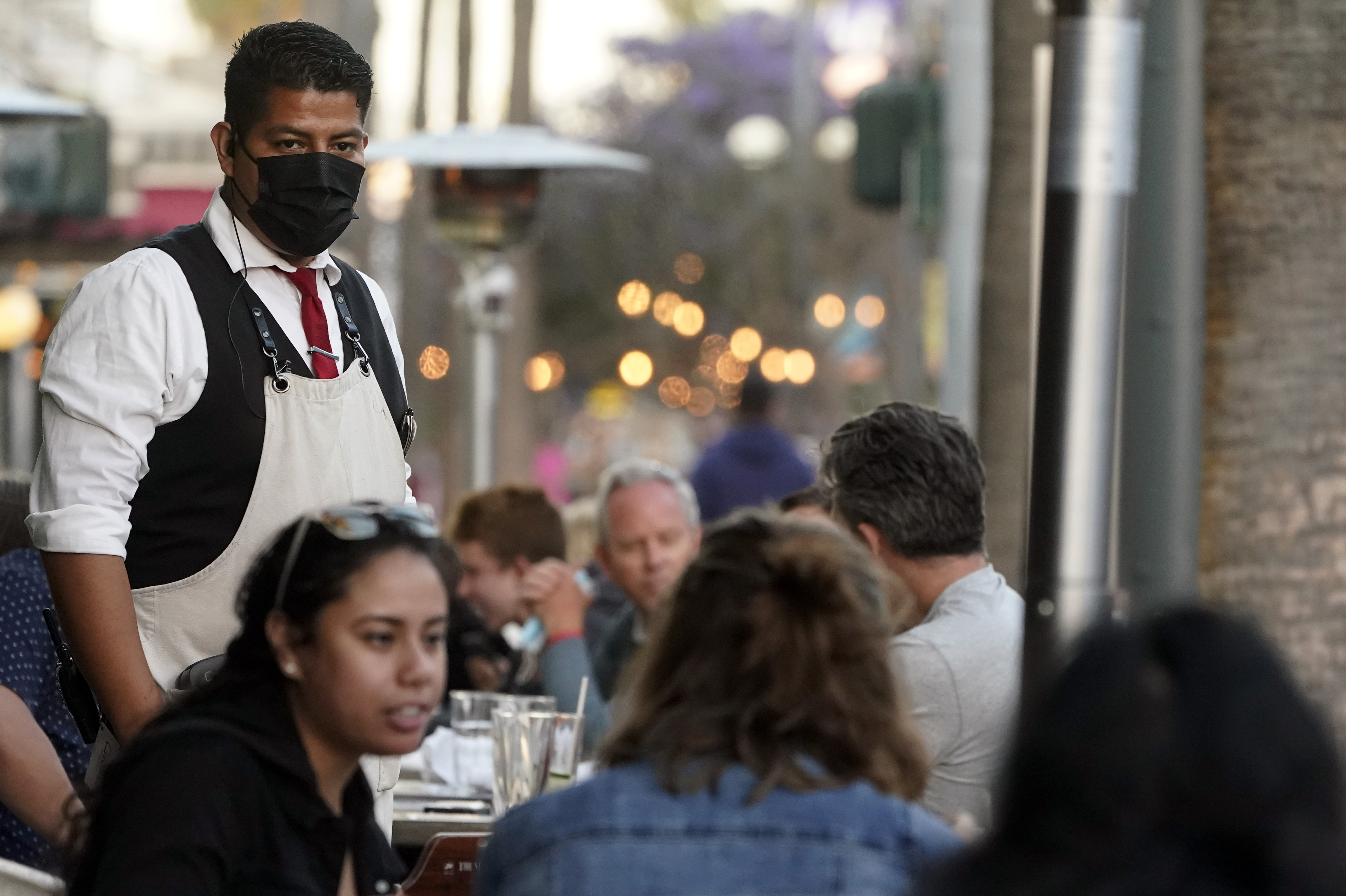FILE - A server tends to customers in an outdoor dining area on The Promenade in Santa Monica, Calif., June 9, 2021. (AP Photo/Marcio Jose Sanchez, File)