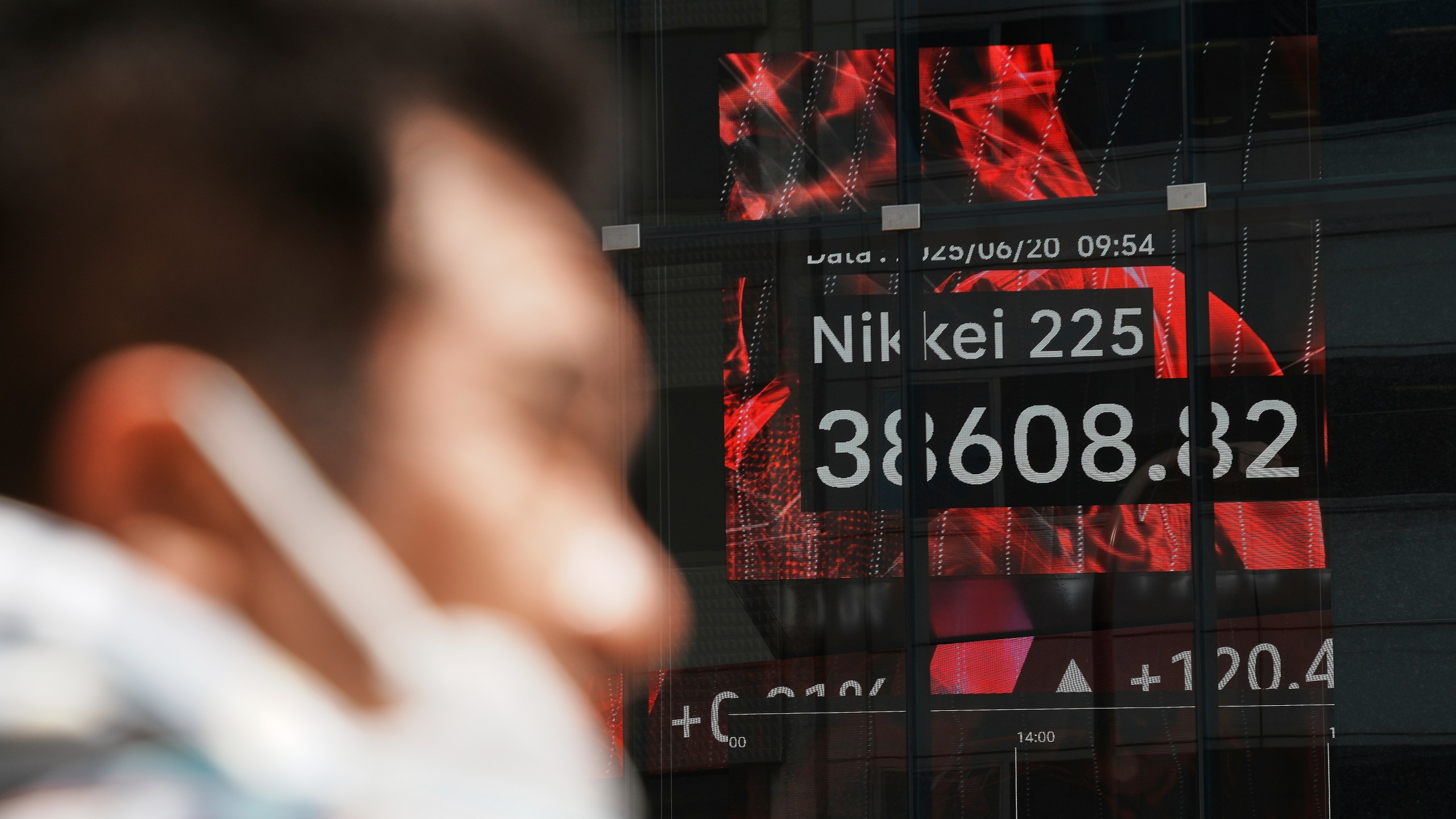 A person stands in front of an electronic stock board showing Japan's Nikkei index at a securities firm Friday, June 20, 2025, in Tokyo. (AP Photo/Eugene Hoshiko)