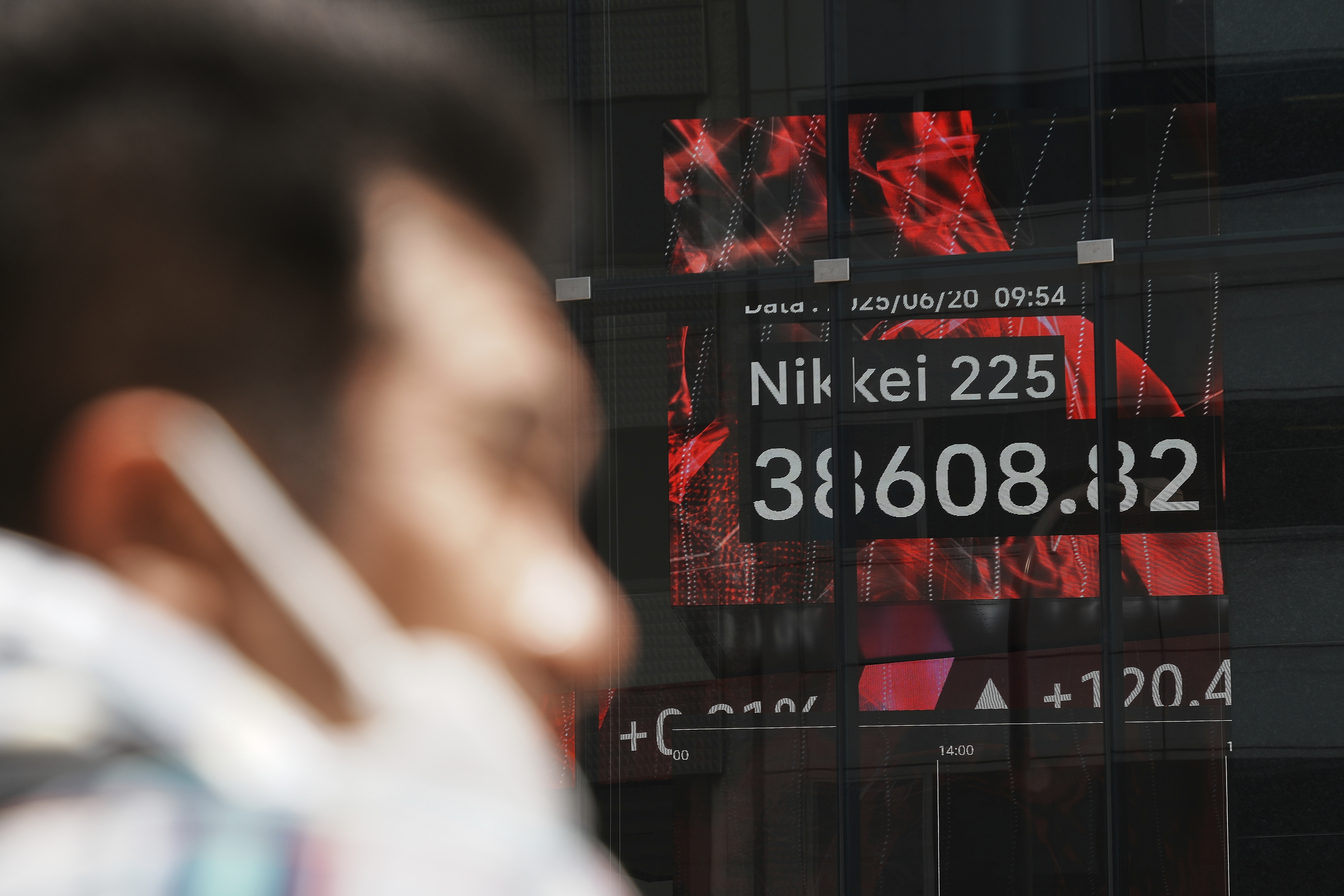 A person stands in front of an electronic stock board showing Japan's Nikkei index at a securities firm Friday, June 20, 2025, in Tokyo. (AP Photo/Eugene Hoshiko)