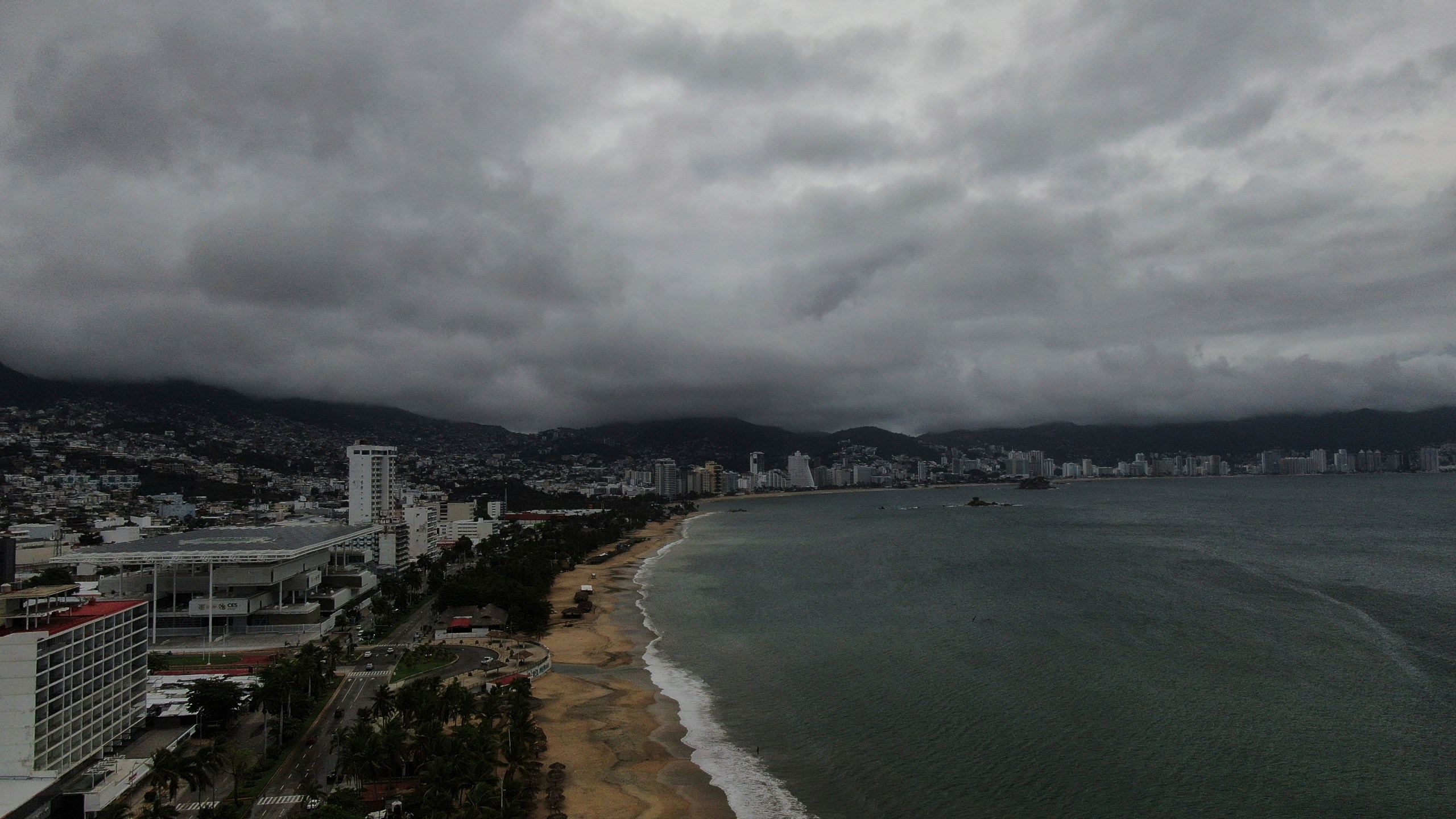 Acapulco Bay is void of boats while they are stored on shore as the nearby passing of Hurricane Erick brings dark clouds, Thursday, June 19, 2025. (AP Photo/Fernando Llano)