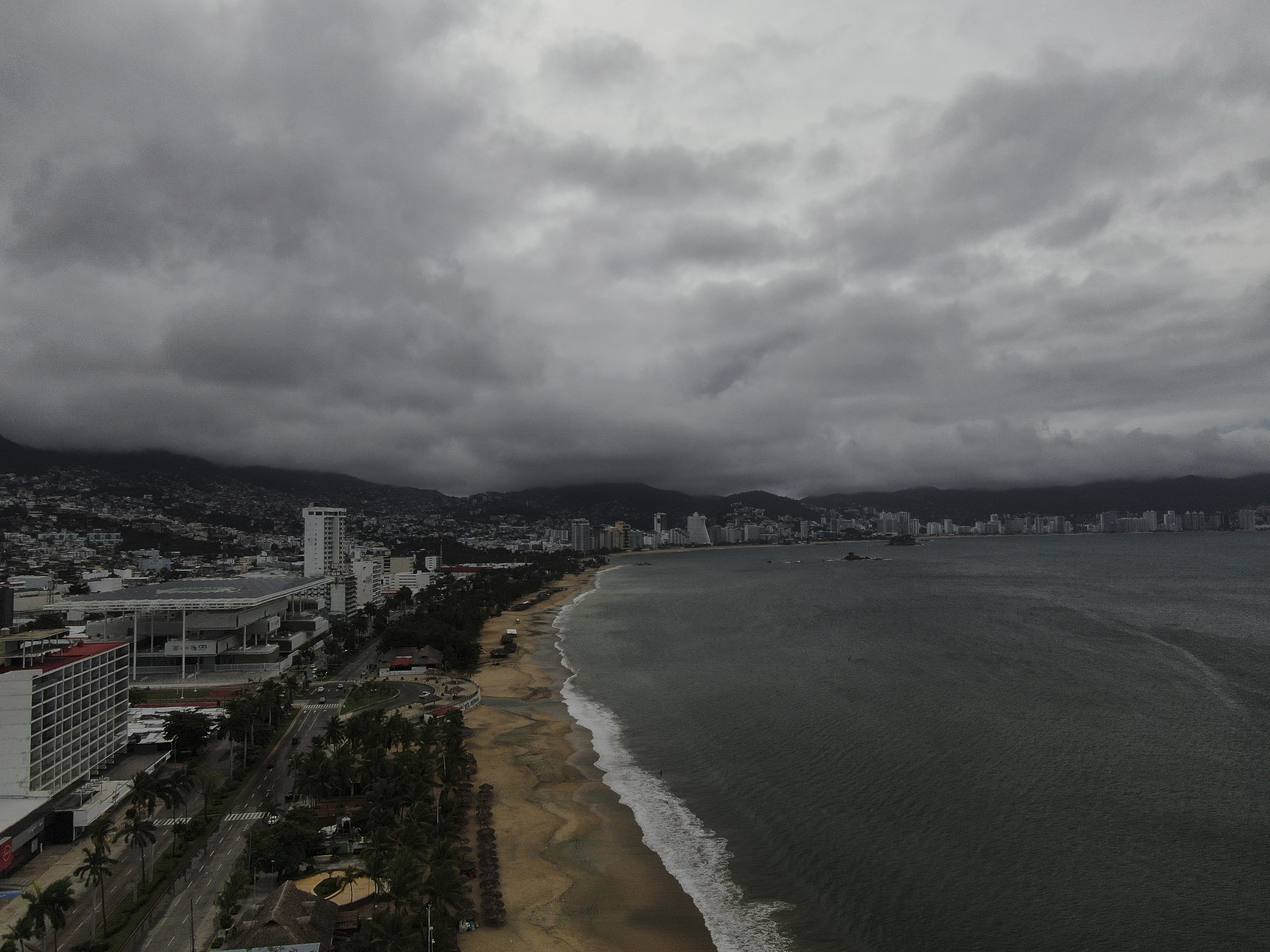 Acapulco Bay is void of boats while they are stored on shore as the nearby passing of Hurricane Erick brings dark clouds, Thursday, June 19, 2025. (AP Photo/Fernando Llano)