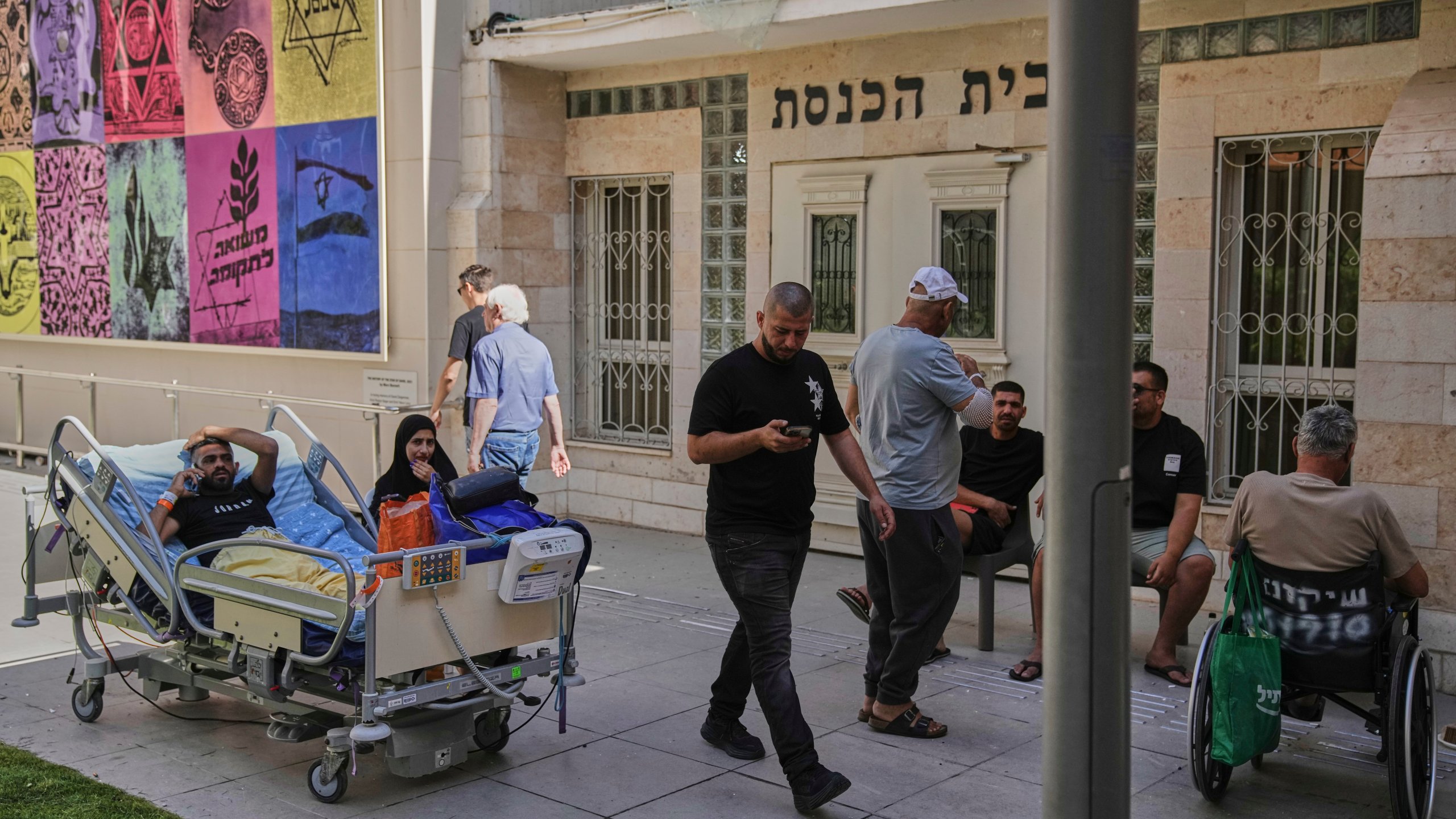 Patients rest outdoors after a building of the Soroka hospital complex was hit by a missile fired from Iran in Beersheba, Israel, Thursday, June 19, 2025. (AP Photo/Leo Correa)