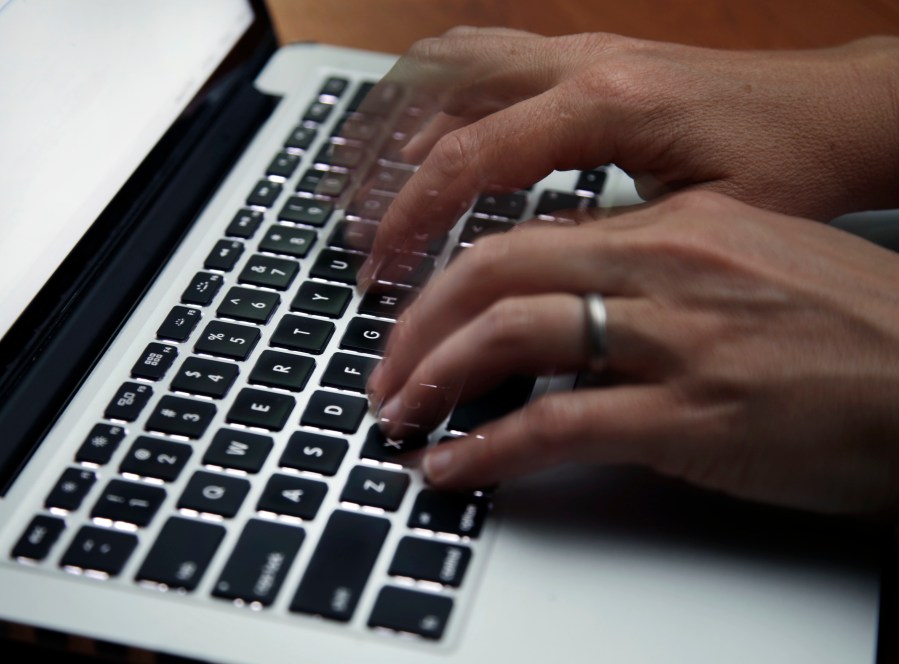 FILE - This June 19, 2017 file photo shows a person working on a laptop in North Andover, Mass. (AP Photo/Elise Amendola, File)