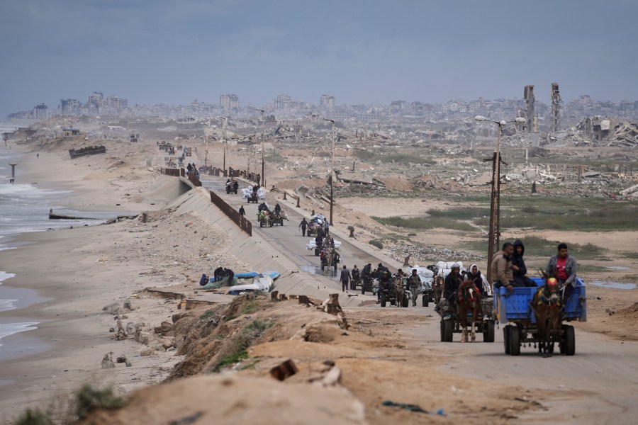 FILE - Displaced Palestinians, carrying their belongings move between southern and northern Gaza along a beach road, in the outskirts of Gaza City, on March 21, 2025. (AP Photo/Abdel Kareem Hana, File)