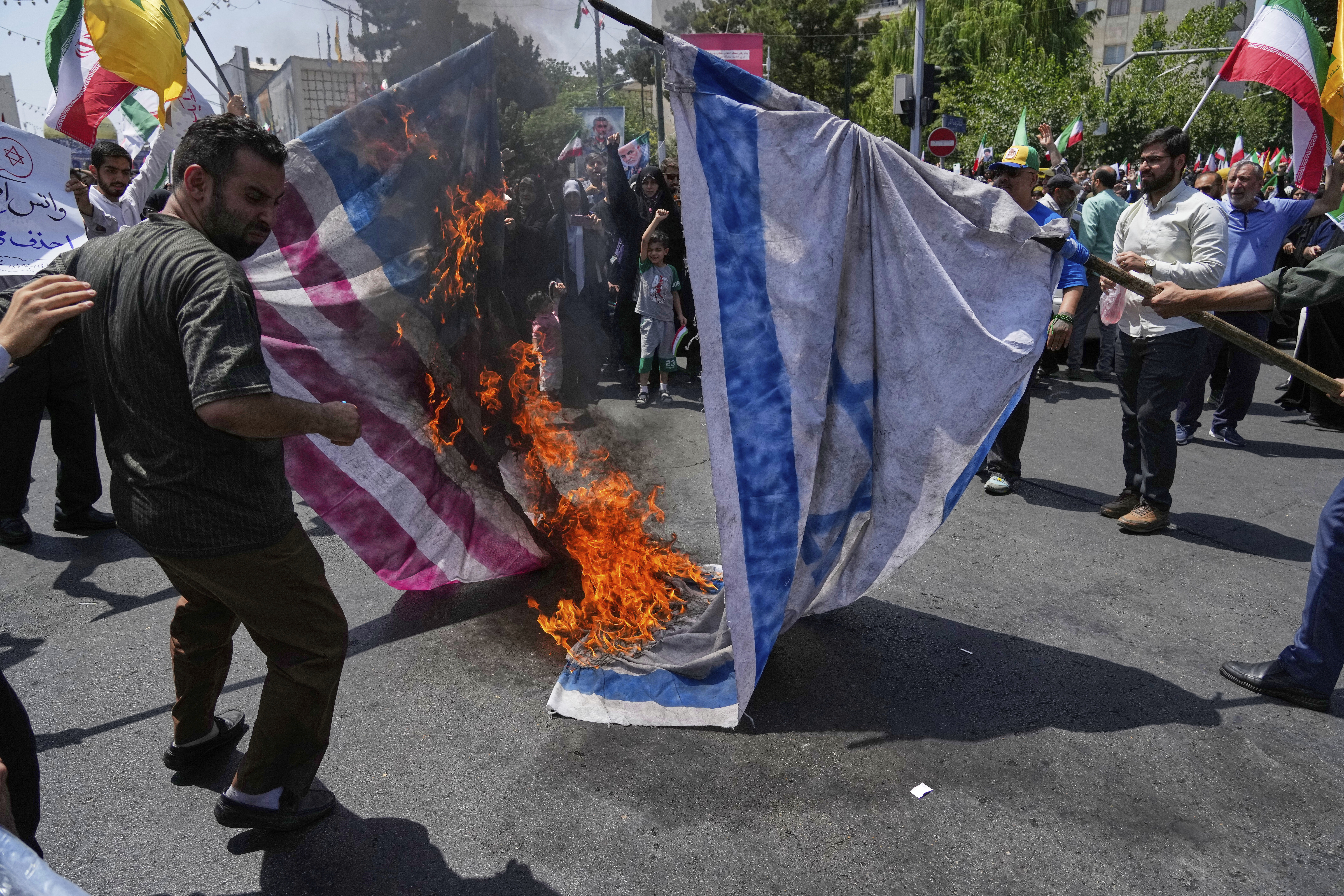 Iranian protestors burn representations of the Israeli and U.S. flags during a protest to condemn Israeli attacks on multiple cities across Iran, after the Friday prayers ceremony in Tehran, Iran, Friday, June 20, 2025. (AP Photo/Vahid Salemi)
