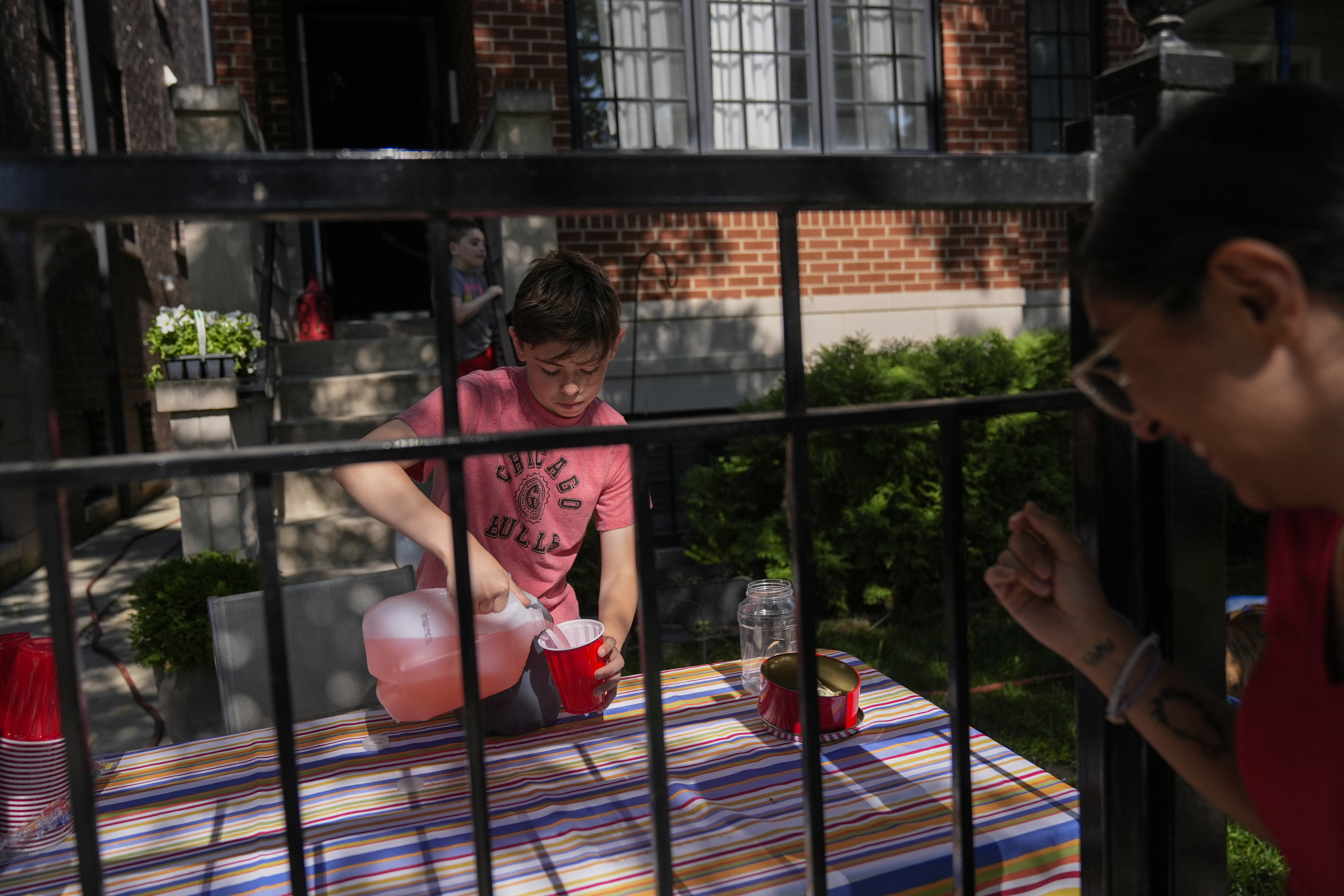 Robby, 12, who did not want to give his last name, sells lemonade in his front yard on a hot Friday, June 20, 2025, in Chicago. (AP Photo/Erin Hooley)