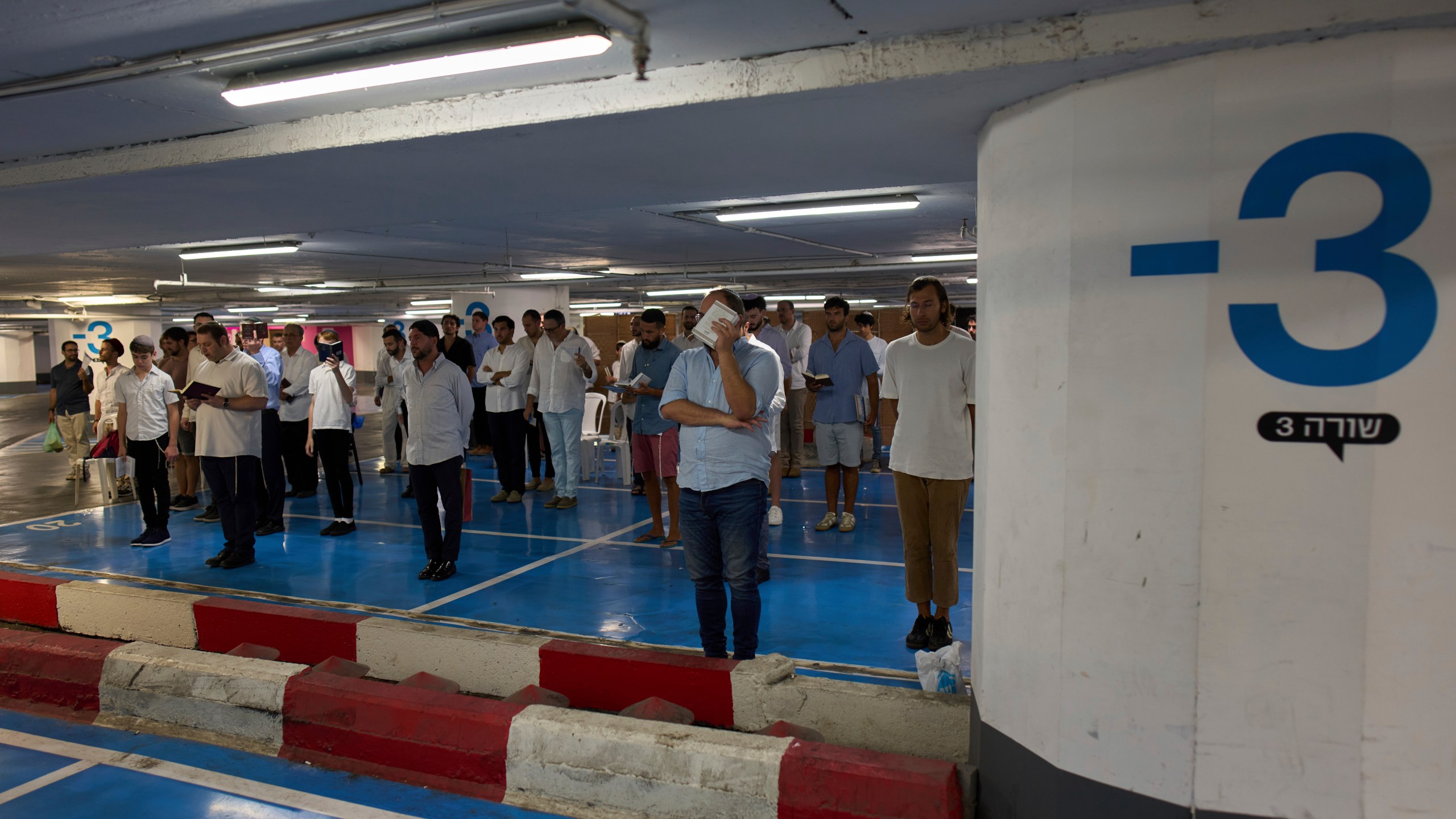 Jewish men attend a Shabbat prayer inside an underground parking for potential protection from missile strikes from Iran, in Tel Aviv, Israel, Friday, June 20, 2025. (AP Photo/Bernat Armangue)