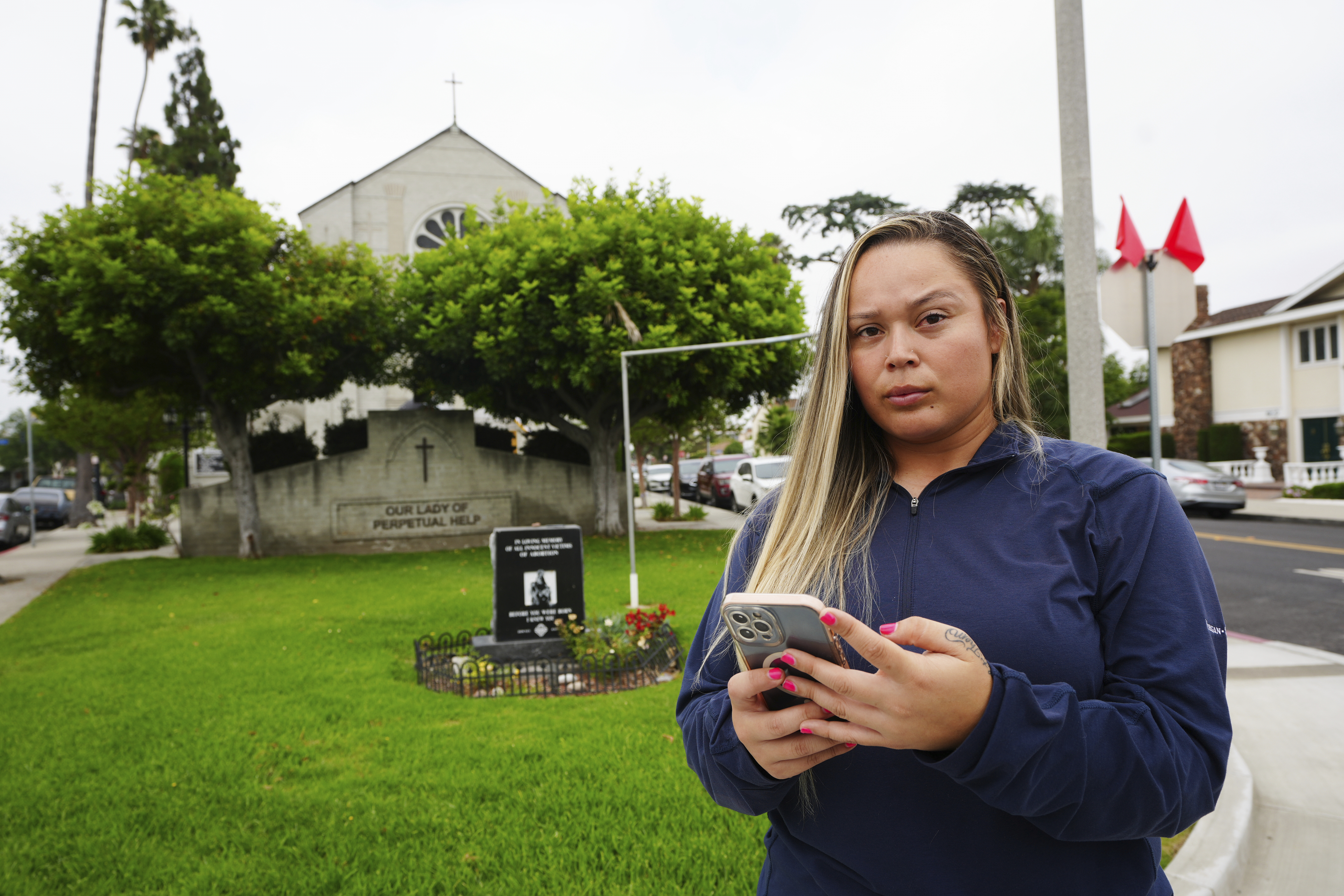 Melyssa Rivas poses for a photo at a location where she witnessed masked federal agents detaining a person earlier this month outside Our Lady of Perpetual Help Catholic Church in Downey, Calif., on Friday, June 20, 2025. (AP Photo/Damian Dovarganes)