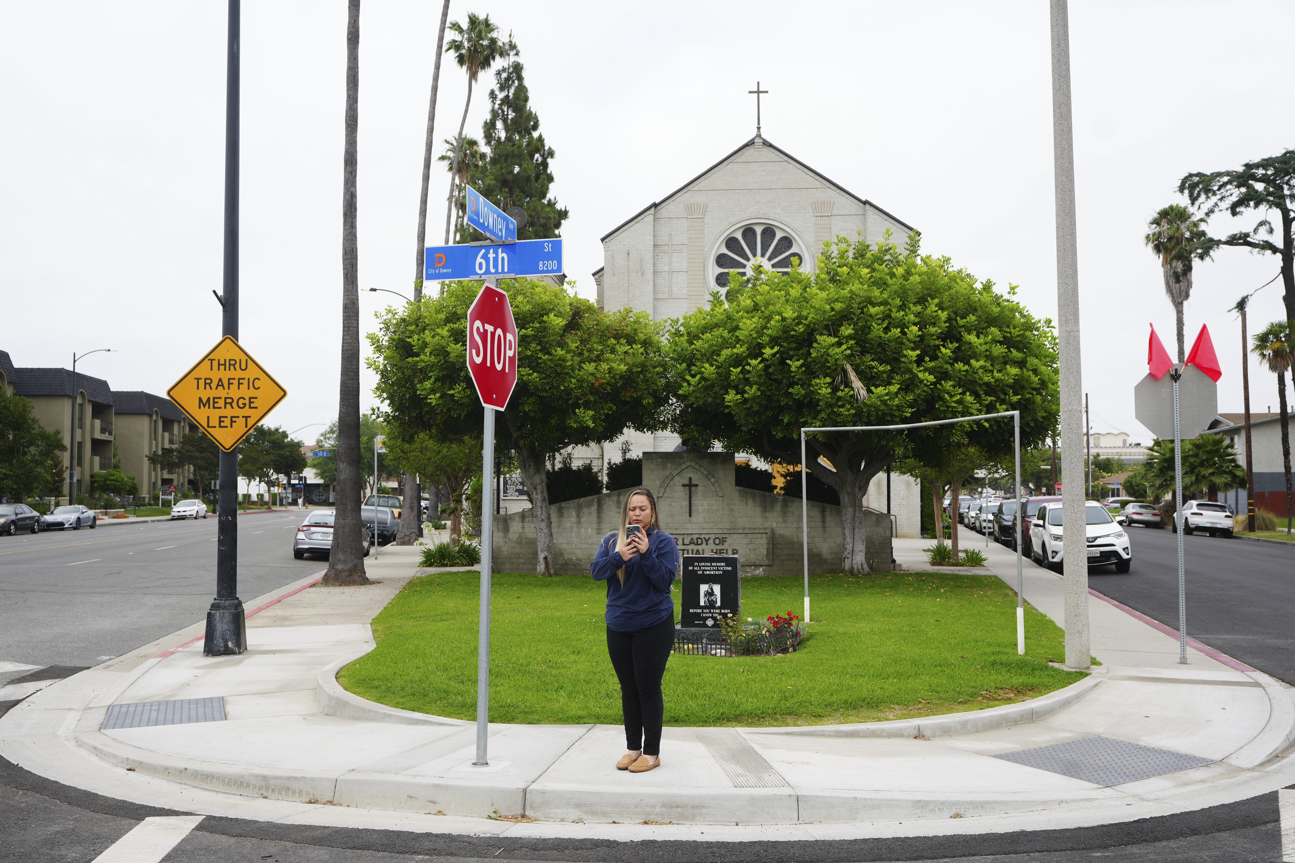 Melyssa Rivas stands at an intersection where she witnessed masked federal agents detaining a person earlier this month outside Our Lady of Perpetual Help Catholic Church in Downey, Calif., on Friday, June 20, 2025. (AP Photo/Damian Dovarganes)