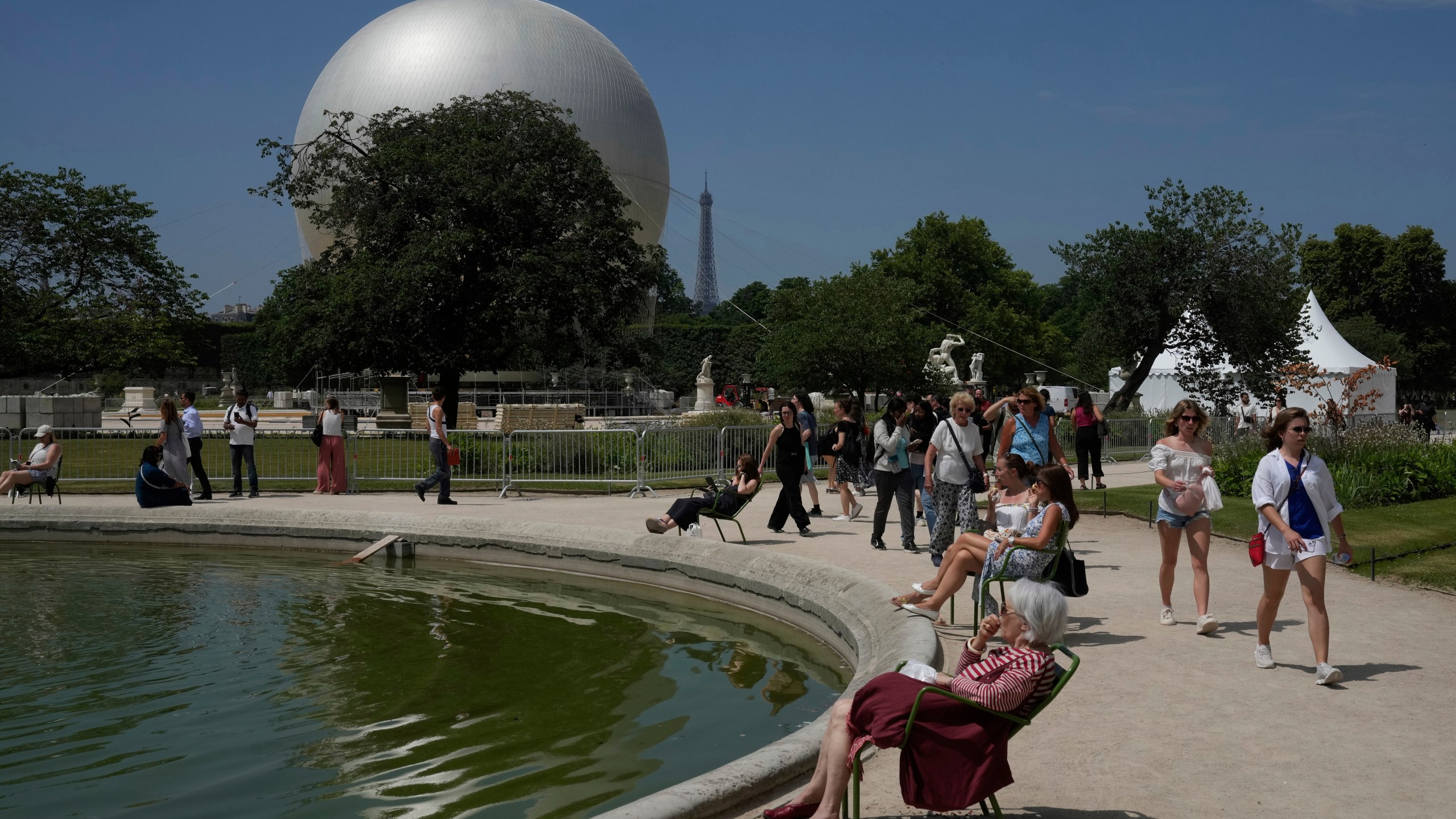 People walk past the Olympic cauldron at the Tuileries Gardens, ahead of its nightly summer relaunch starting June 21, in Paris, Thursday, June 12, 2025. (AP Photo/Michel Euler)