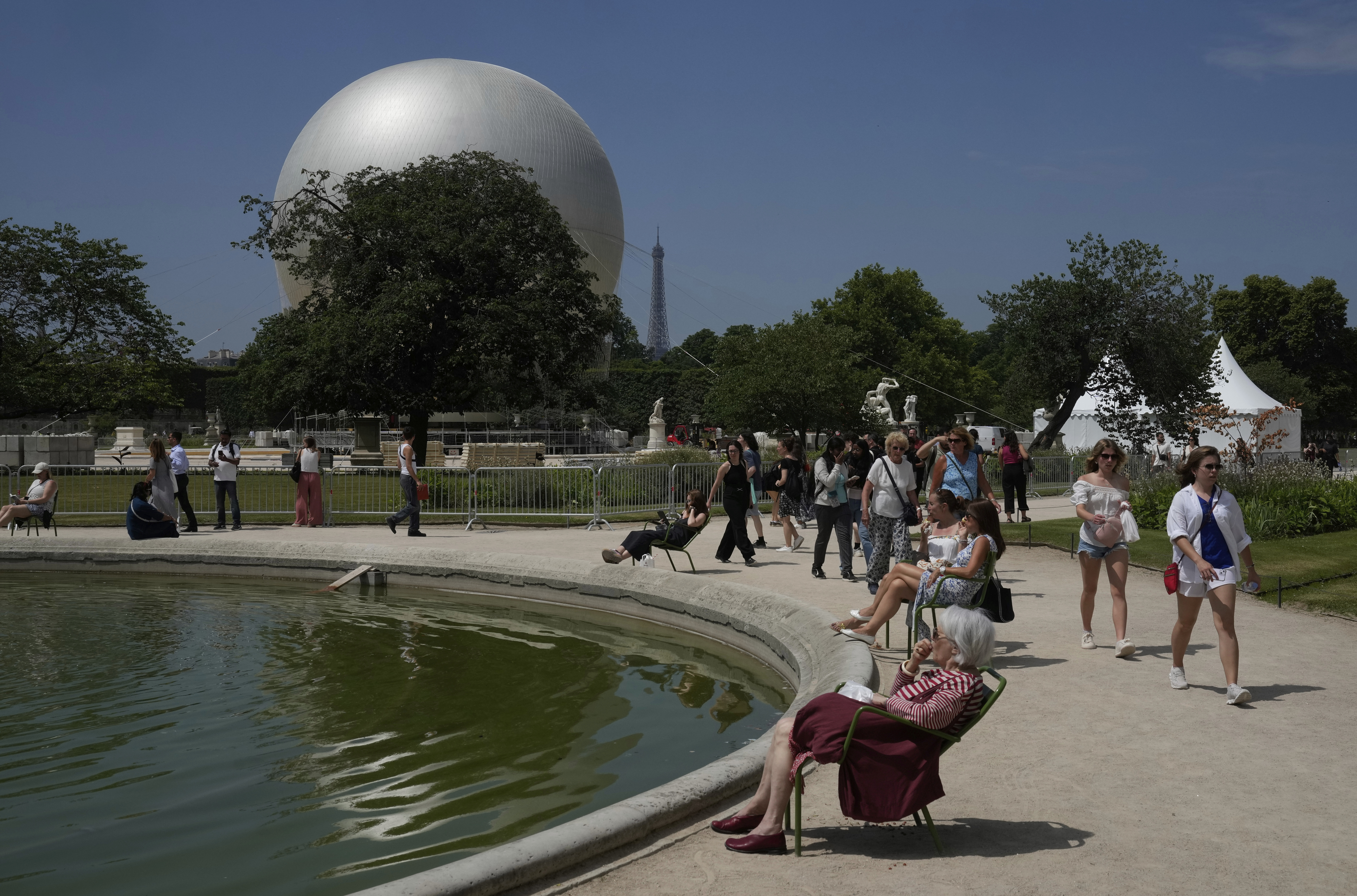 People walk past the Olympic cauldron at the Tuileries Gardens, ahead of its nightly summer relaunch starting June 21, in Paris, Thursday, June 12, 2025. (AP Photo/Michel Euler)