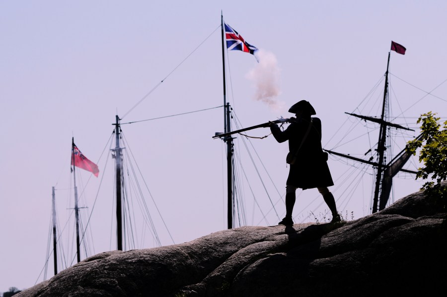 A Colonial soldier fires on the British during a reenactment in celebration of the 250th anniversary of the Battle of Bunker Hill, Saturday, June 21, 2025, in Gloucester, Mass. (AP Photo/Charles Krupa)