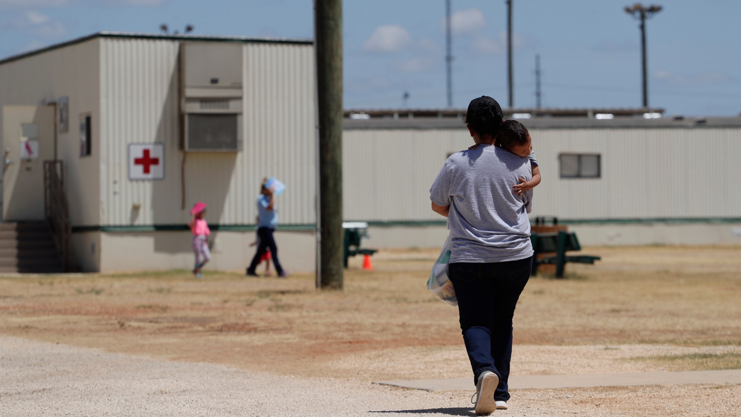 FILE - Immigrants seeking asylum walk at the ICE South Texas Family Residential Center, Aug. 23, 2019, in Dilley, Texas. (AP Photo/Eric Gay, File)