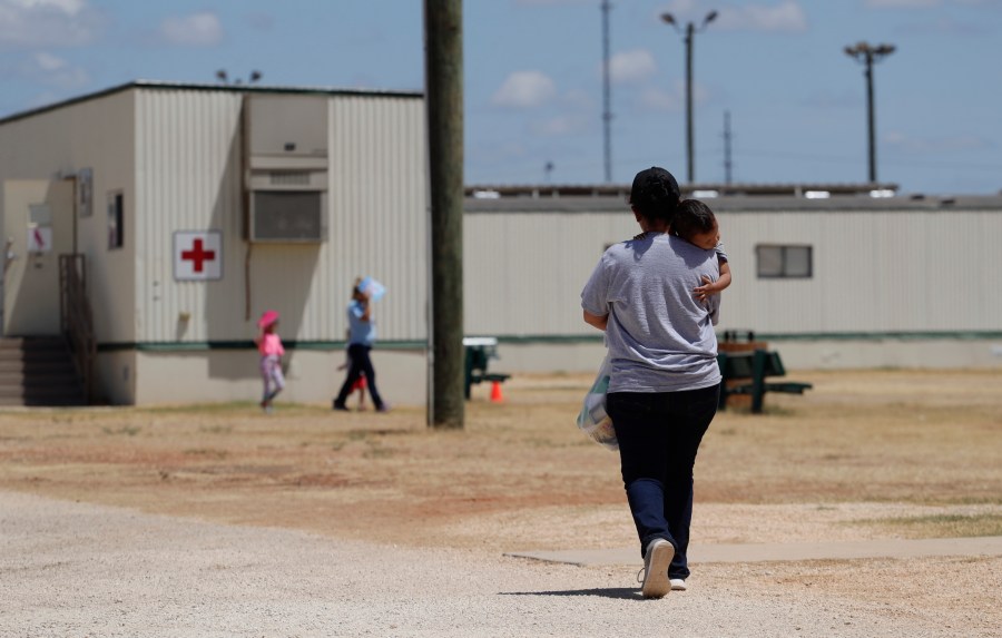 FILE - Immigrants seeking asylum walk at the ICE South Texas Family Residential Center, Aug. 23, 2019, in Dilley, Texas. (AP Photo/Eric Gay, File)
