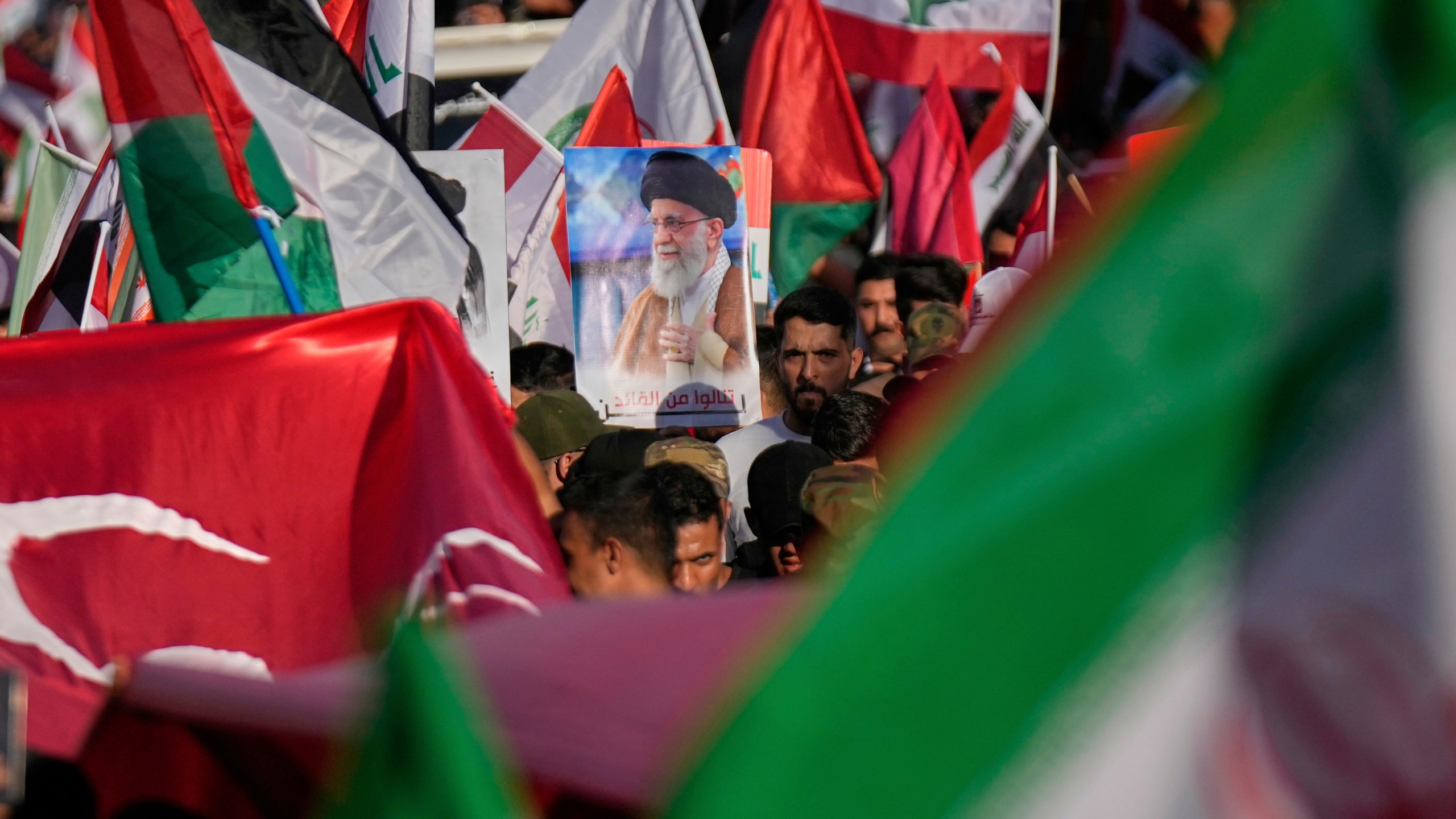 A protest holds a portrait of Iran's Supreme Leader Ayatollah Ali Khamenei during a rally to show solidarity with Iran in the Shi'ite district of Kazimiyah, in Baghdad, Iraq, Saturday, June 21, 2025. (AP Photo/Hadi Mizban)