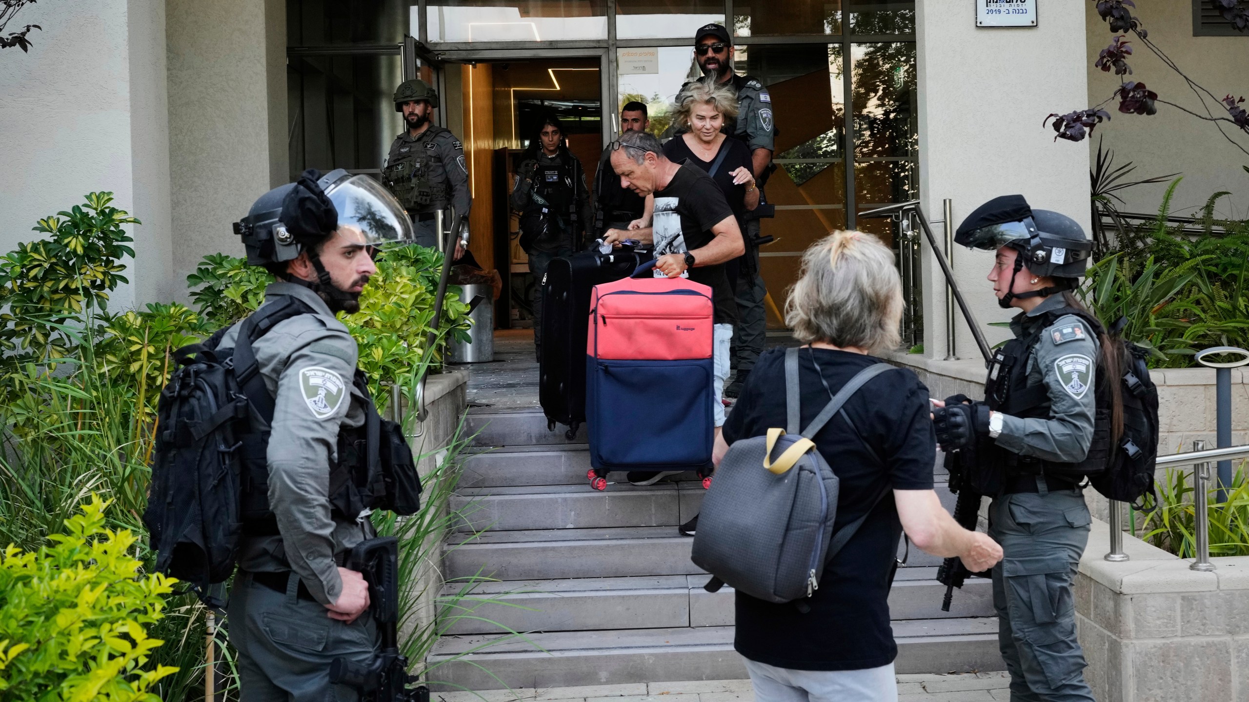 Israeli border police officers help residents to evacuate from a building damaged in an Iranian missile strike in Tel Aviv, Israel, Sunday, June 22, 2025. (AP Photo/Bernat Armangue)
